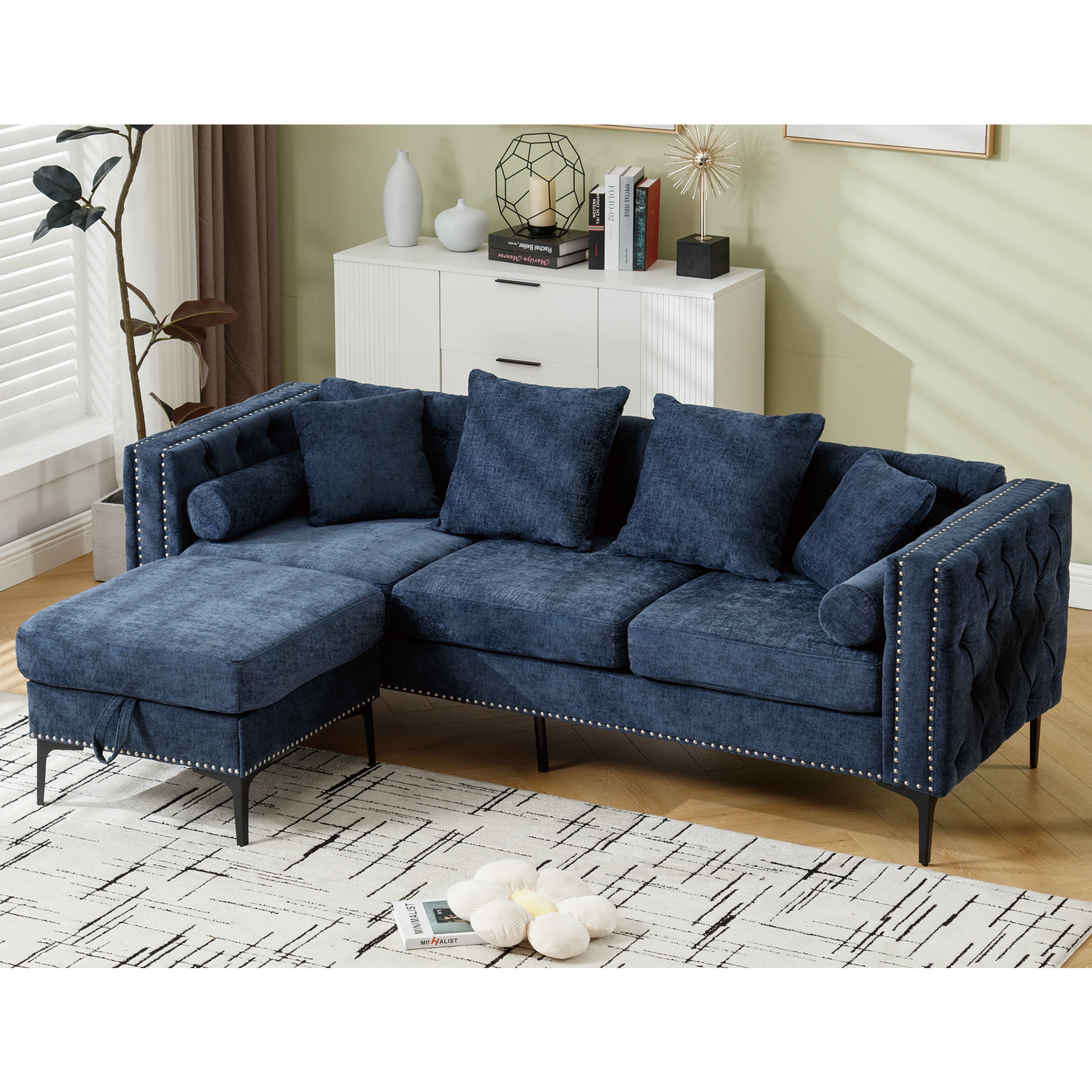 Deep blue tufted sectional sofa with silver nailhead trim featuring plush cushions and a chaise ottoman for living room seating