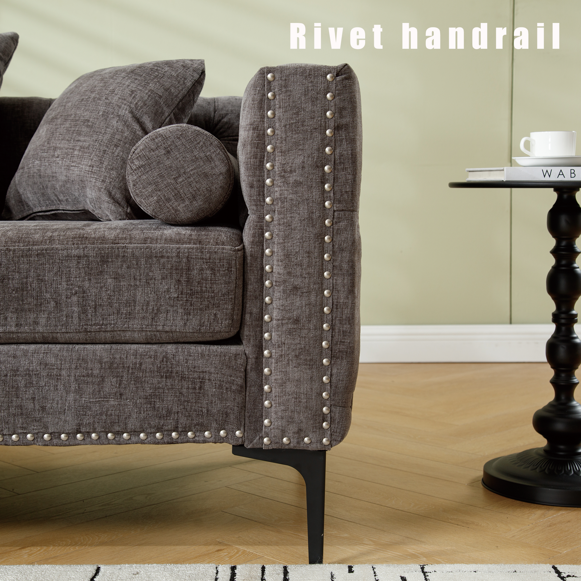 Dark gray upholstered sofa with decorative silver rivets on armrest