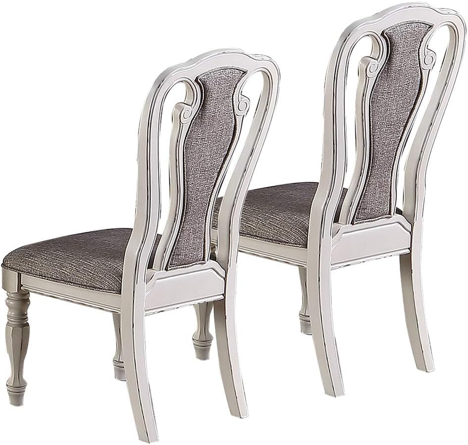 Two ornate dining chairs with light gray upholstered seats and backs and a distressed white wooden frame