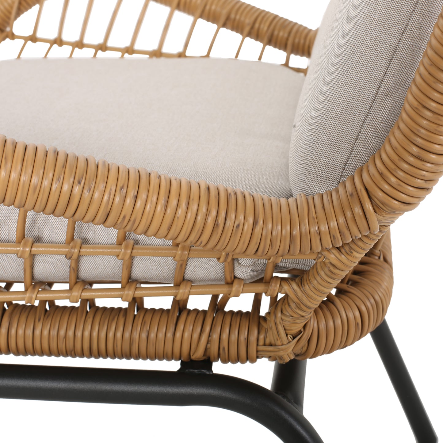Closeup of a light grey cushioned rattan armchair with a textured weave and black metal legs