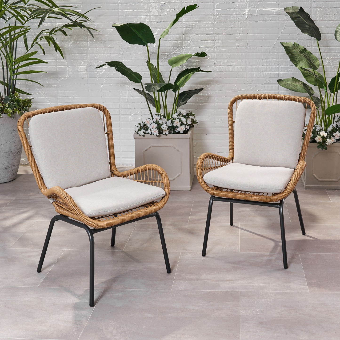 Two natural rattan outdoor chairs with light cream cushions and black metal legs