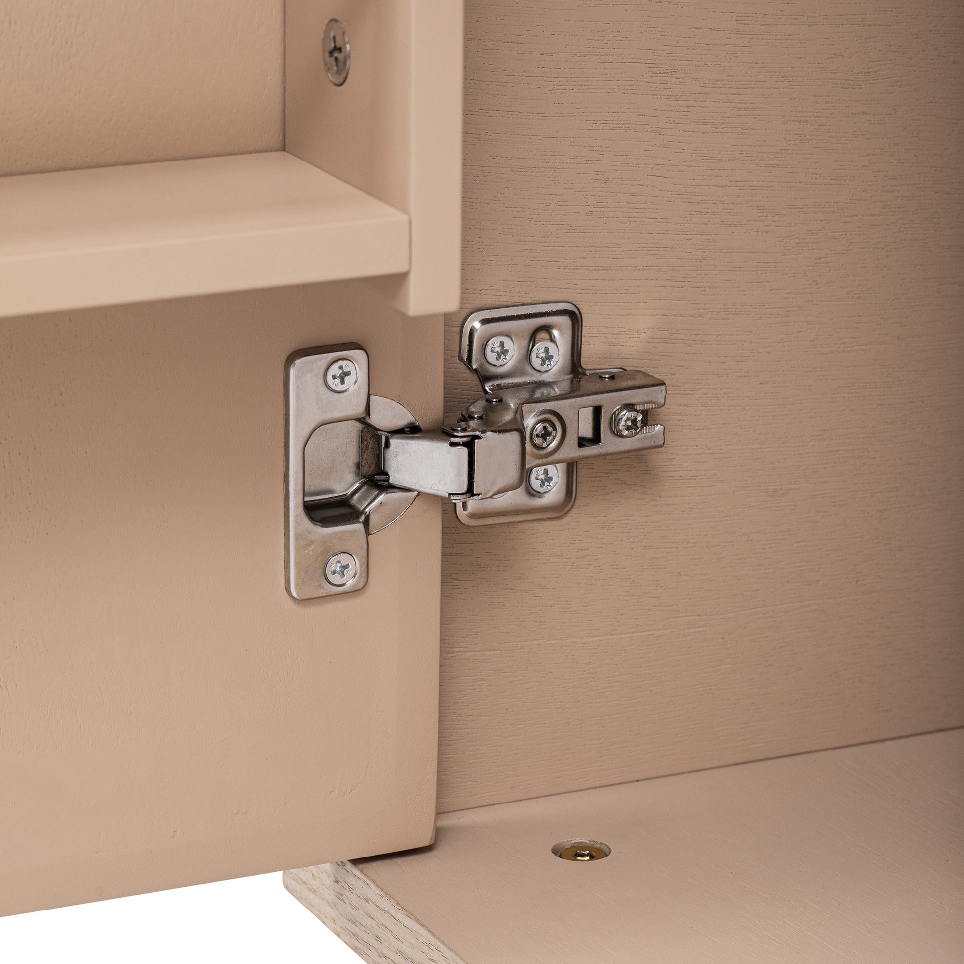 Detail of a brushed nickel cabinet hinge on a tan wood grain door