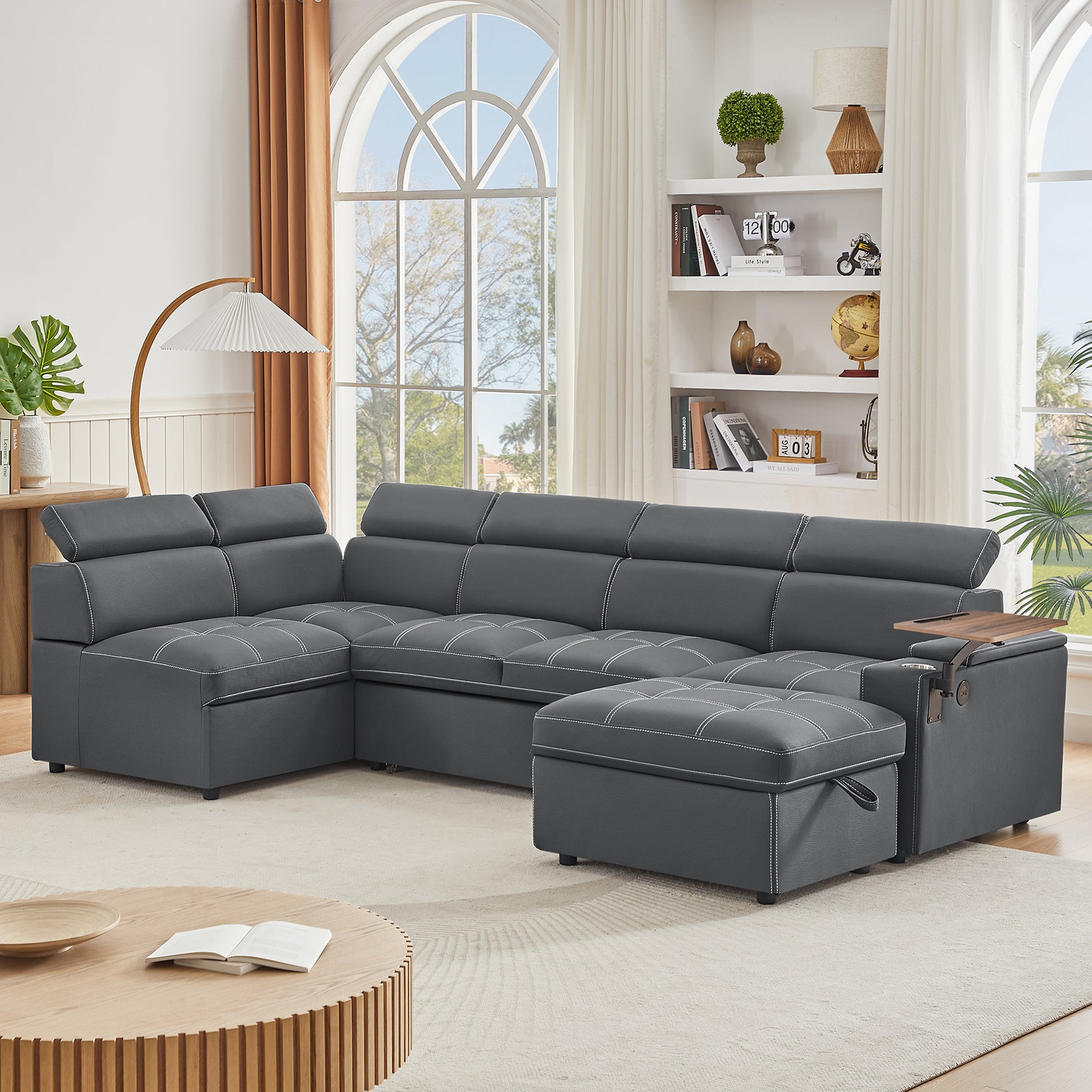 Dark gray sectional sofa with white stitching adjustable headrests and builtin storage ottoman