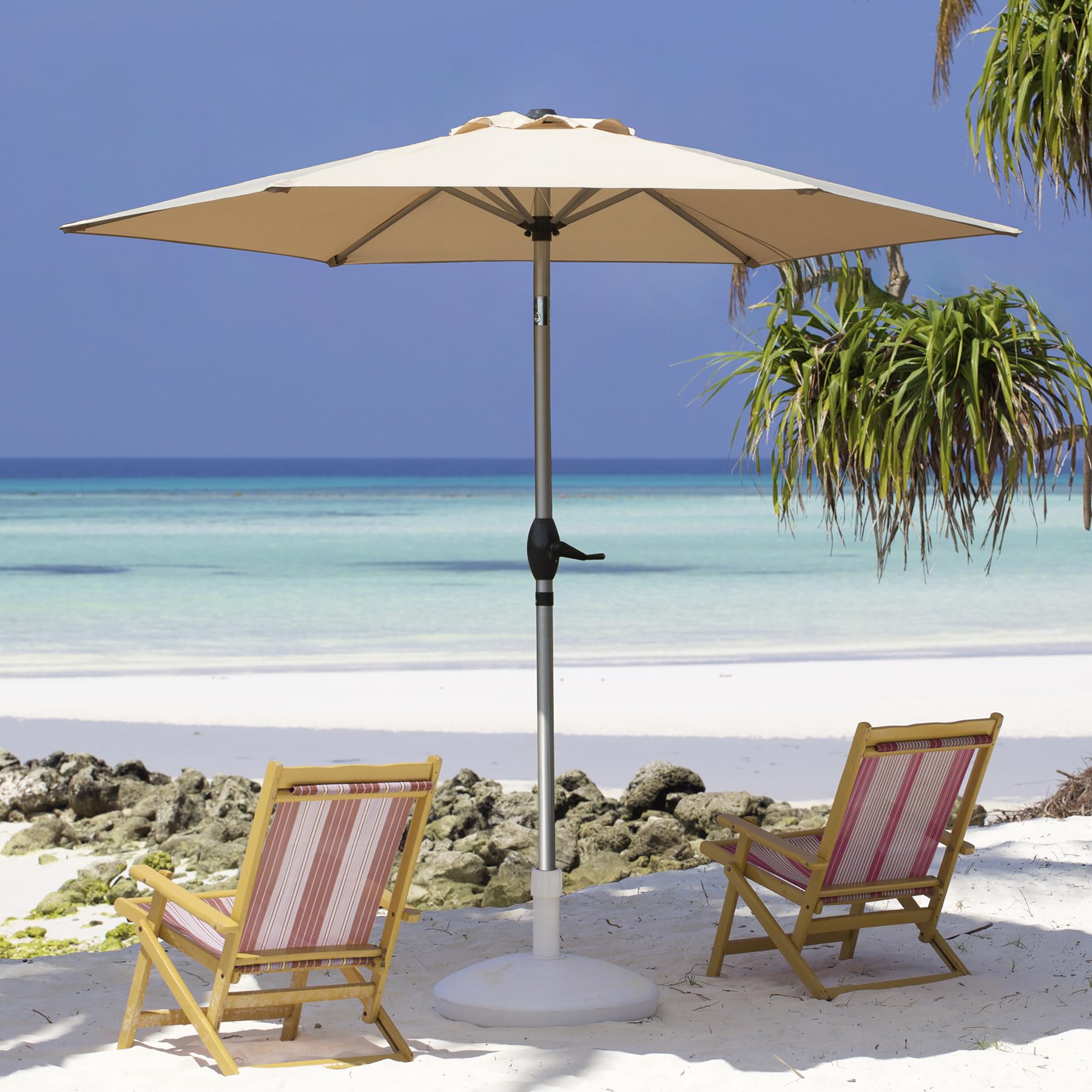 Beige patio umbrella with tilt mechanism and striped beach chairs