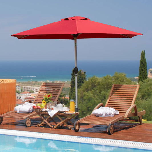 Red patio umbrella provides shade over two wooden lounge chairs with breakfast service