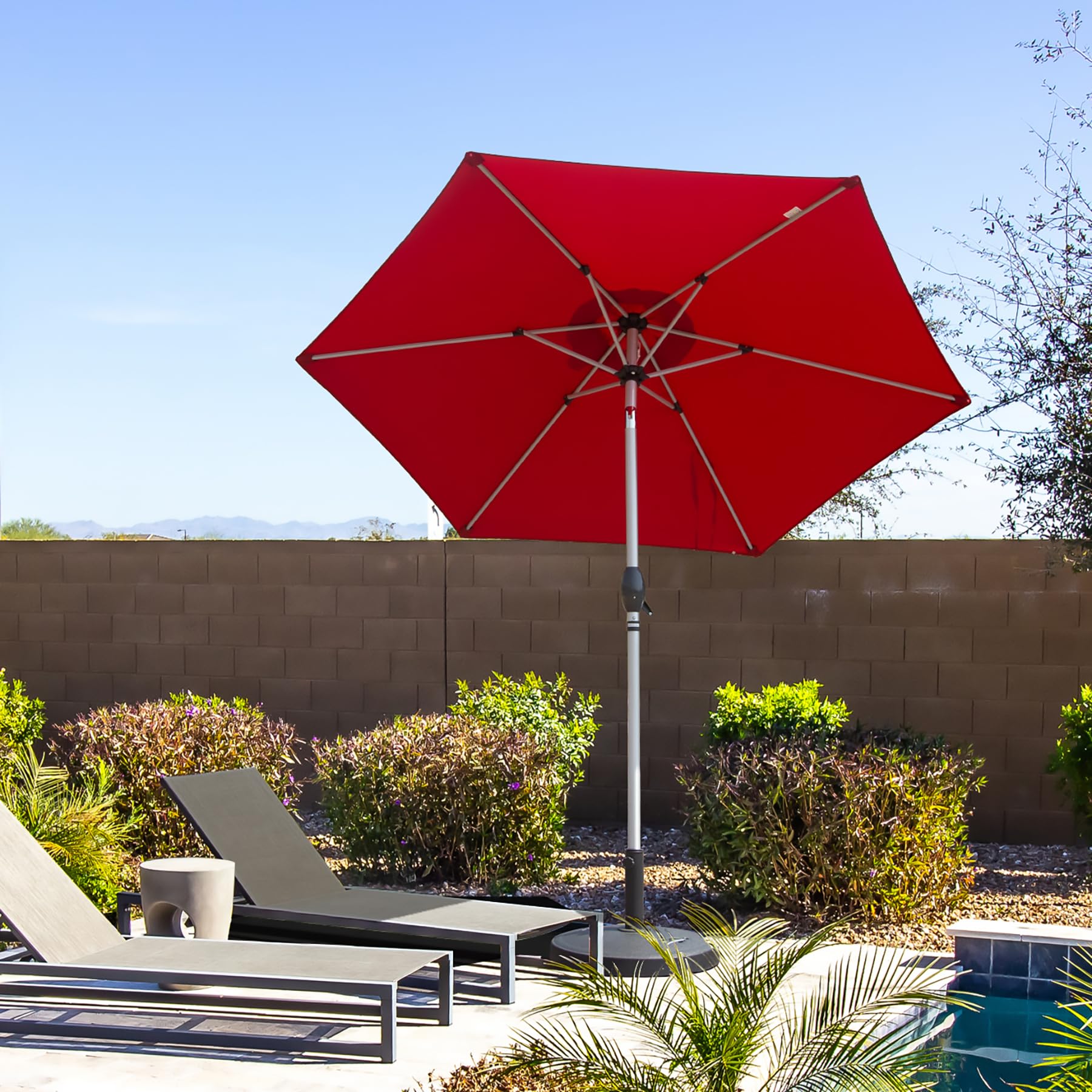 Red octagonal patio umbrella providing shade for outdoor lounge chairs