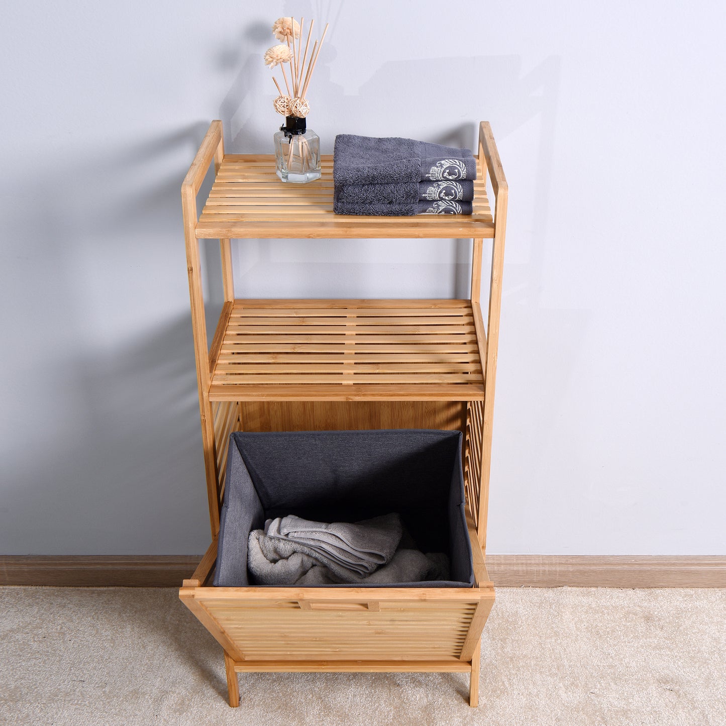 Natural bamboo shelving unit with a grey laundry basket and folded towels