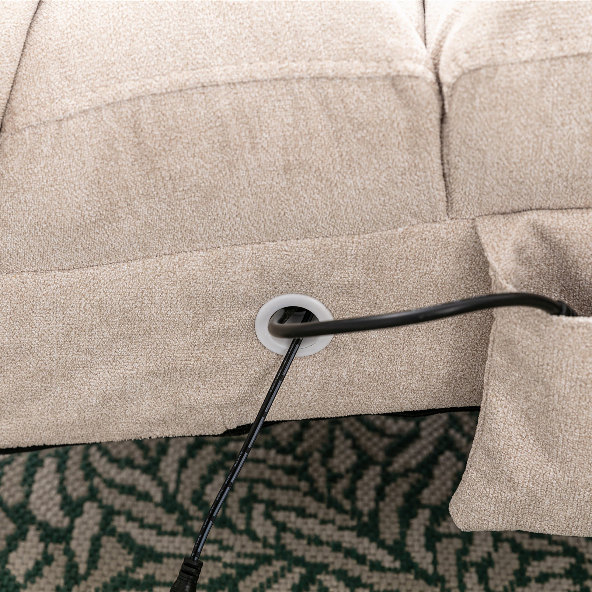 Close up of beige upholstered sofa with a cord management grommet and a black cable