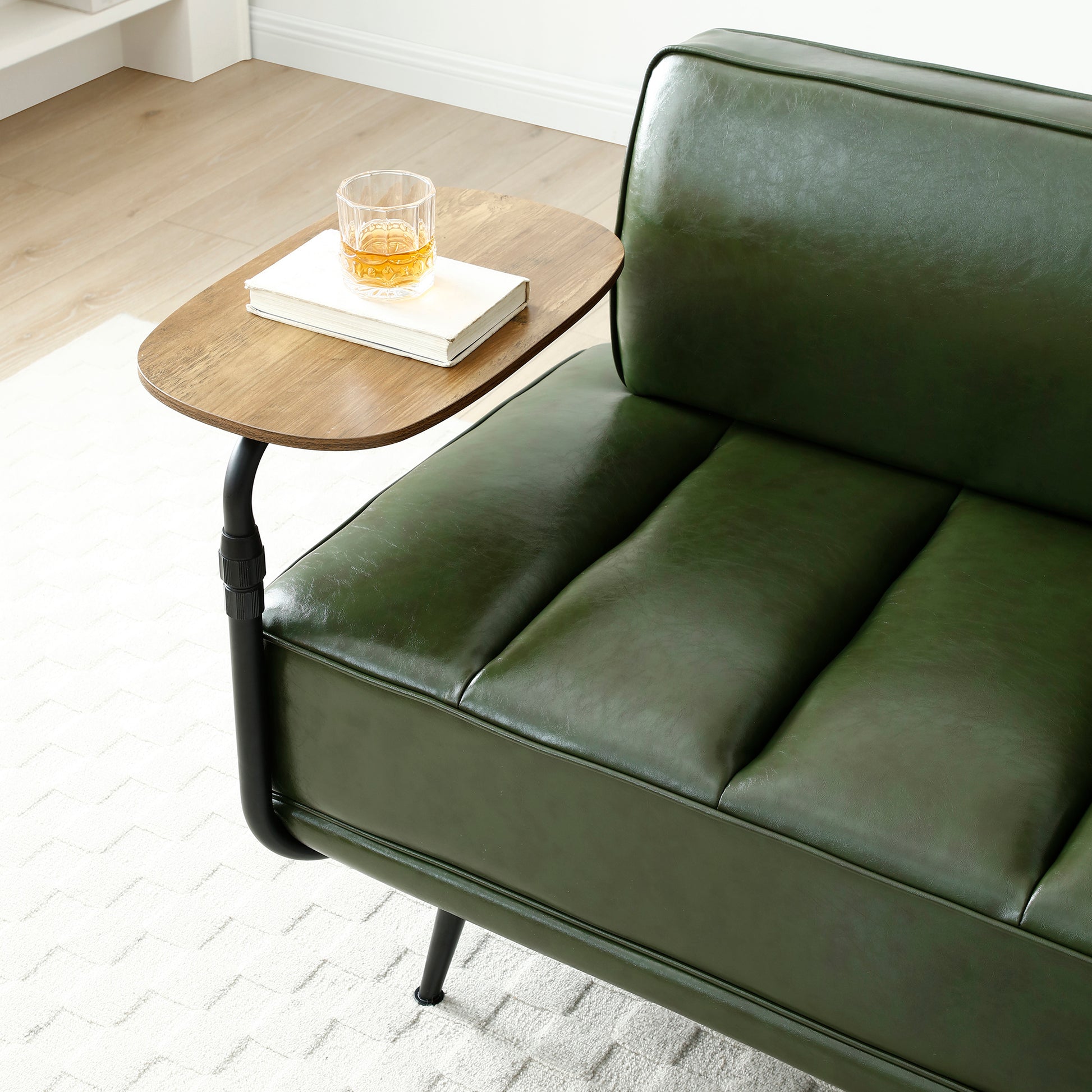 Forest green faux leather sofa with tufted seat cushions and a wooden side table