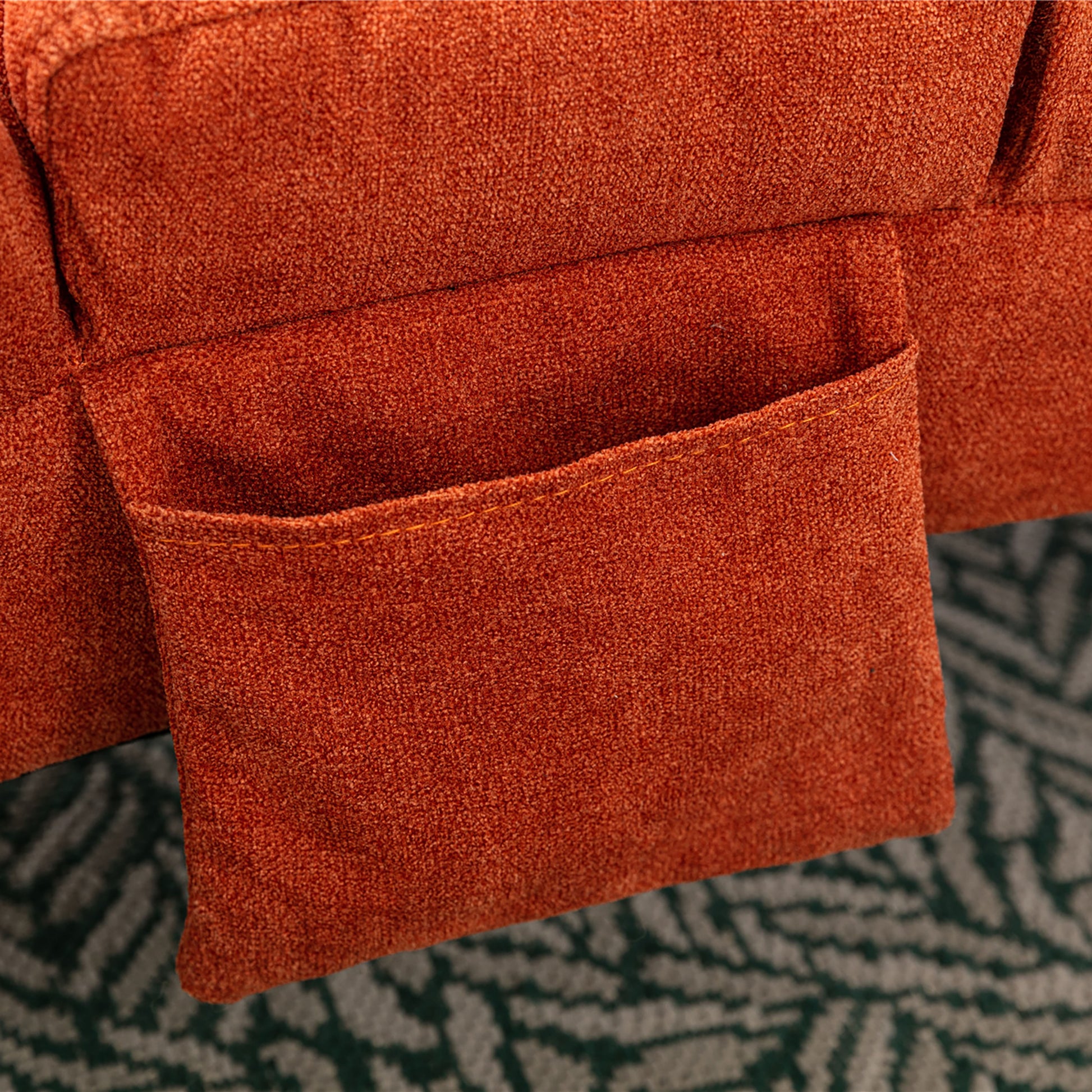 Closeup of an orange textured fabric sofa arm with a convenient side pocket for storage
