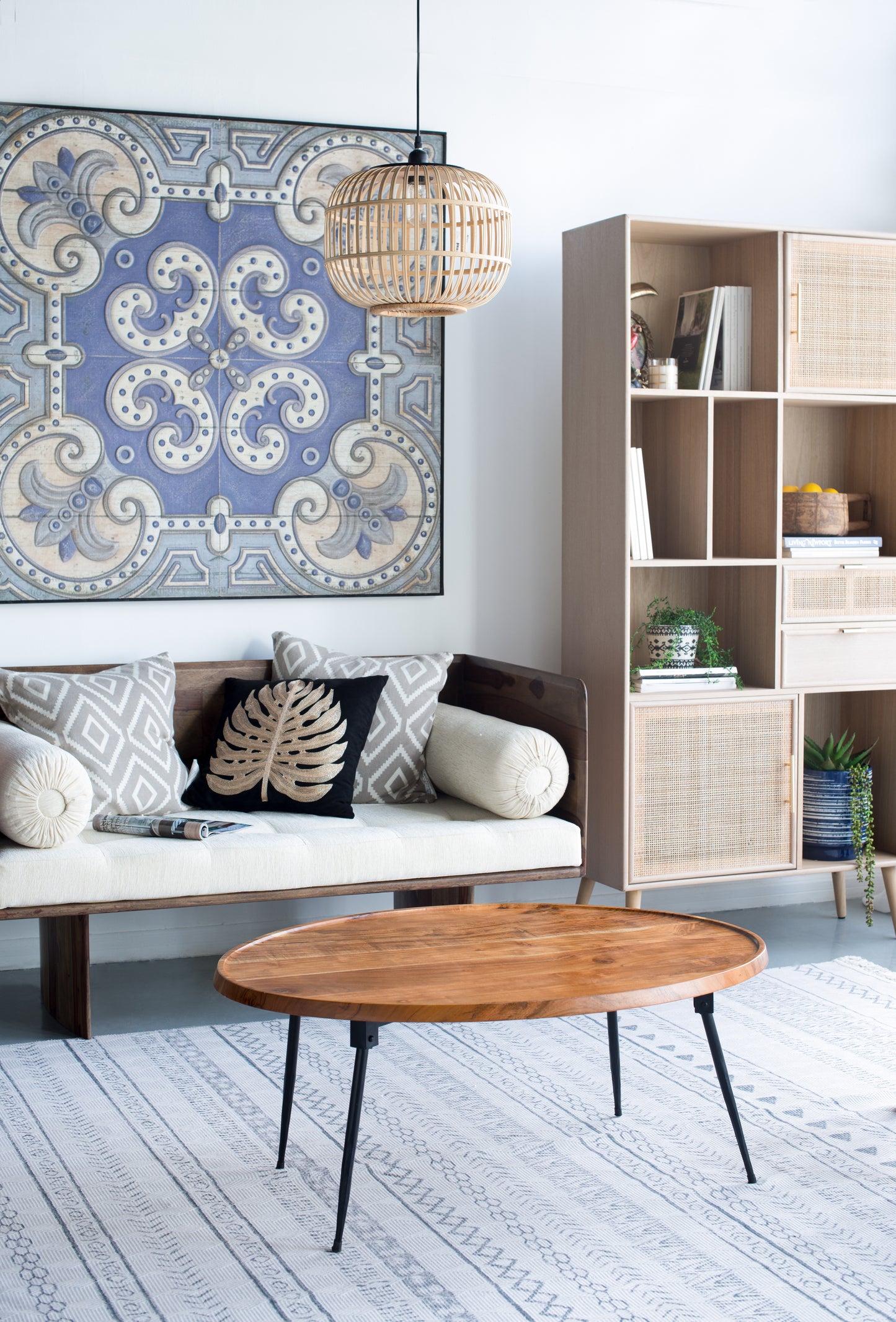 Bohemian style woven bamboo pendant light fixture with exposed bulb illuminating a living space