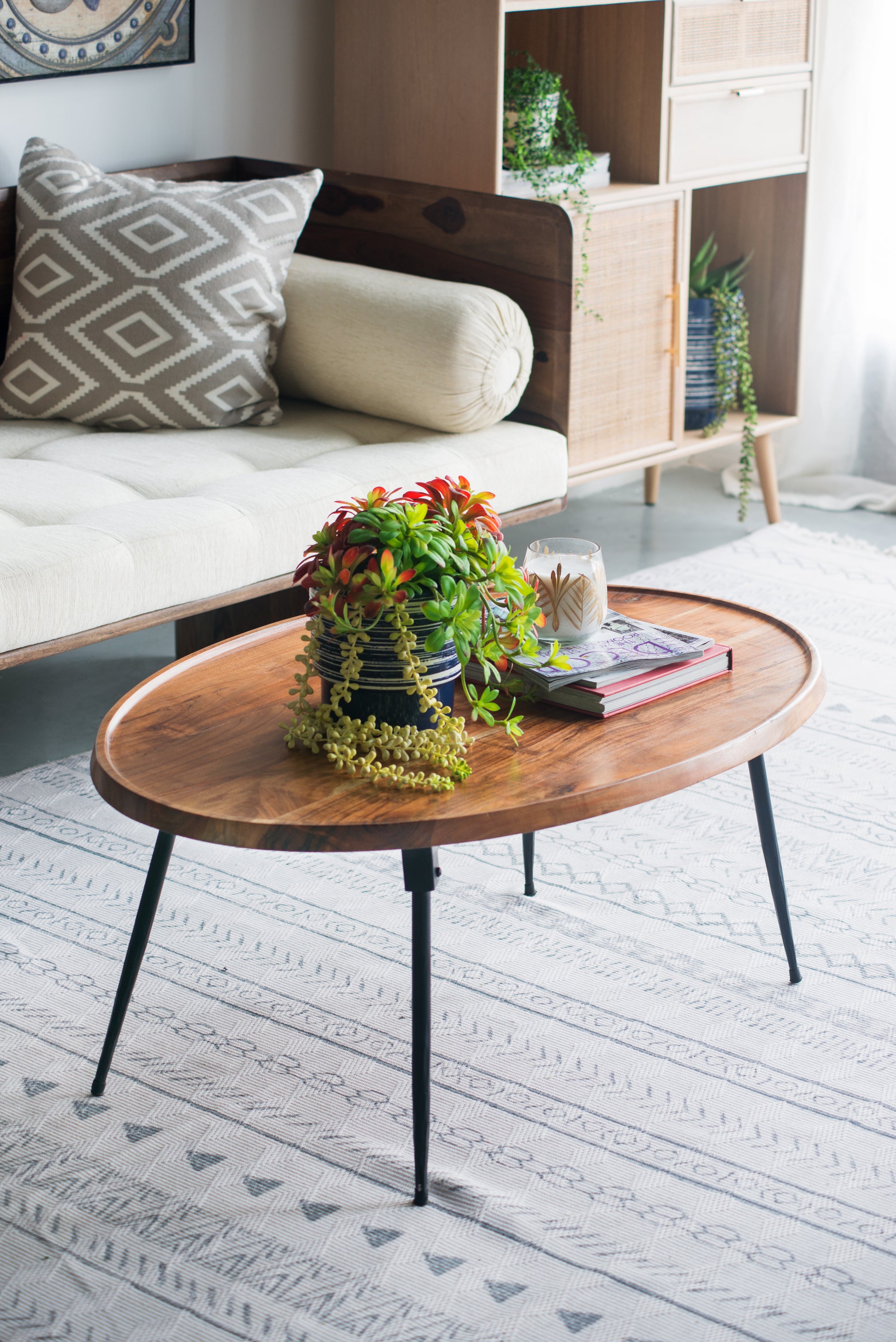 Oval wood coffee table with black metal legs and decorative plant