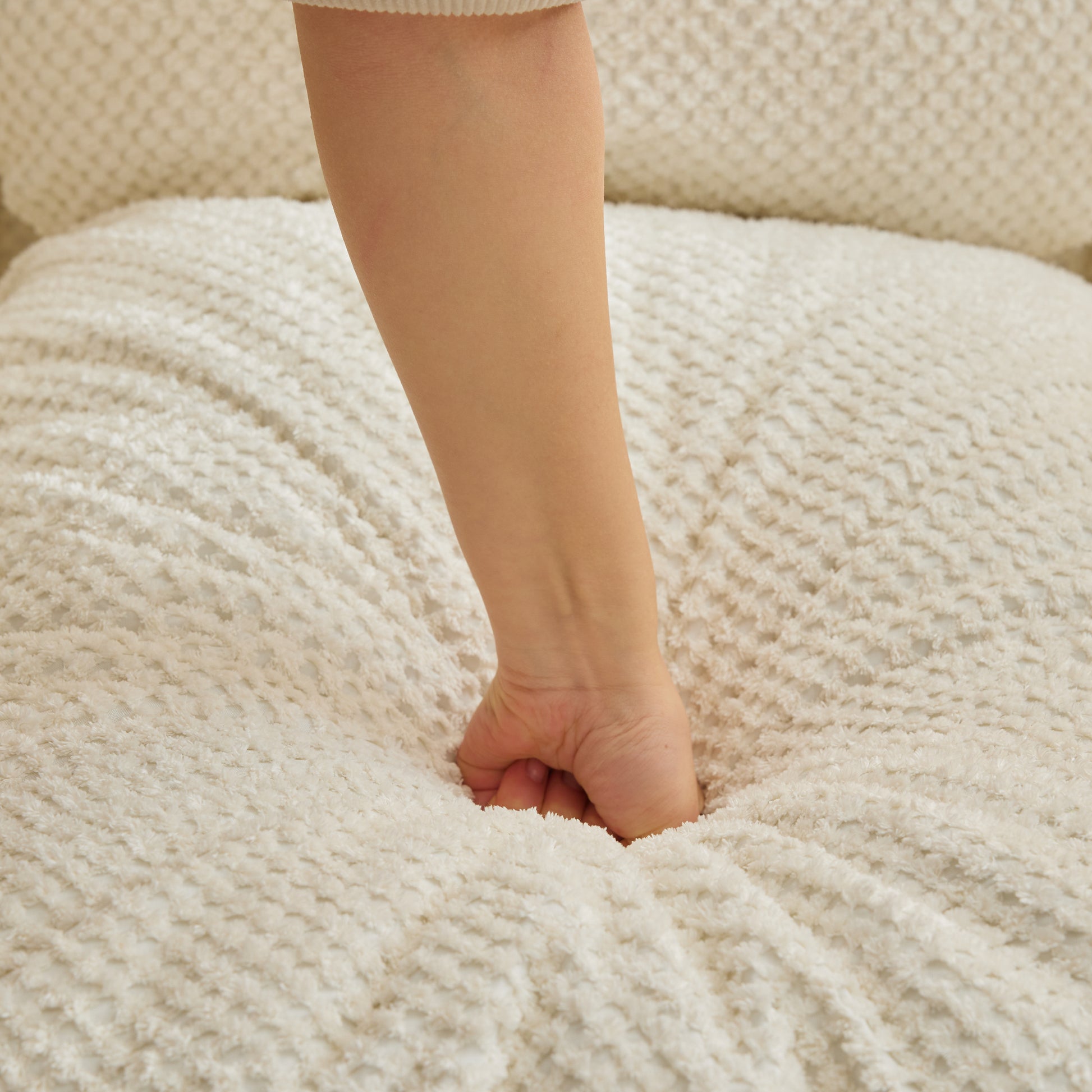 Plush cream sherpa pet bed showing its soft sinkable texture with a hand pressing in