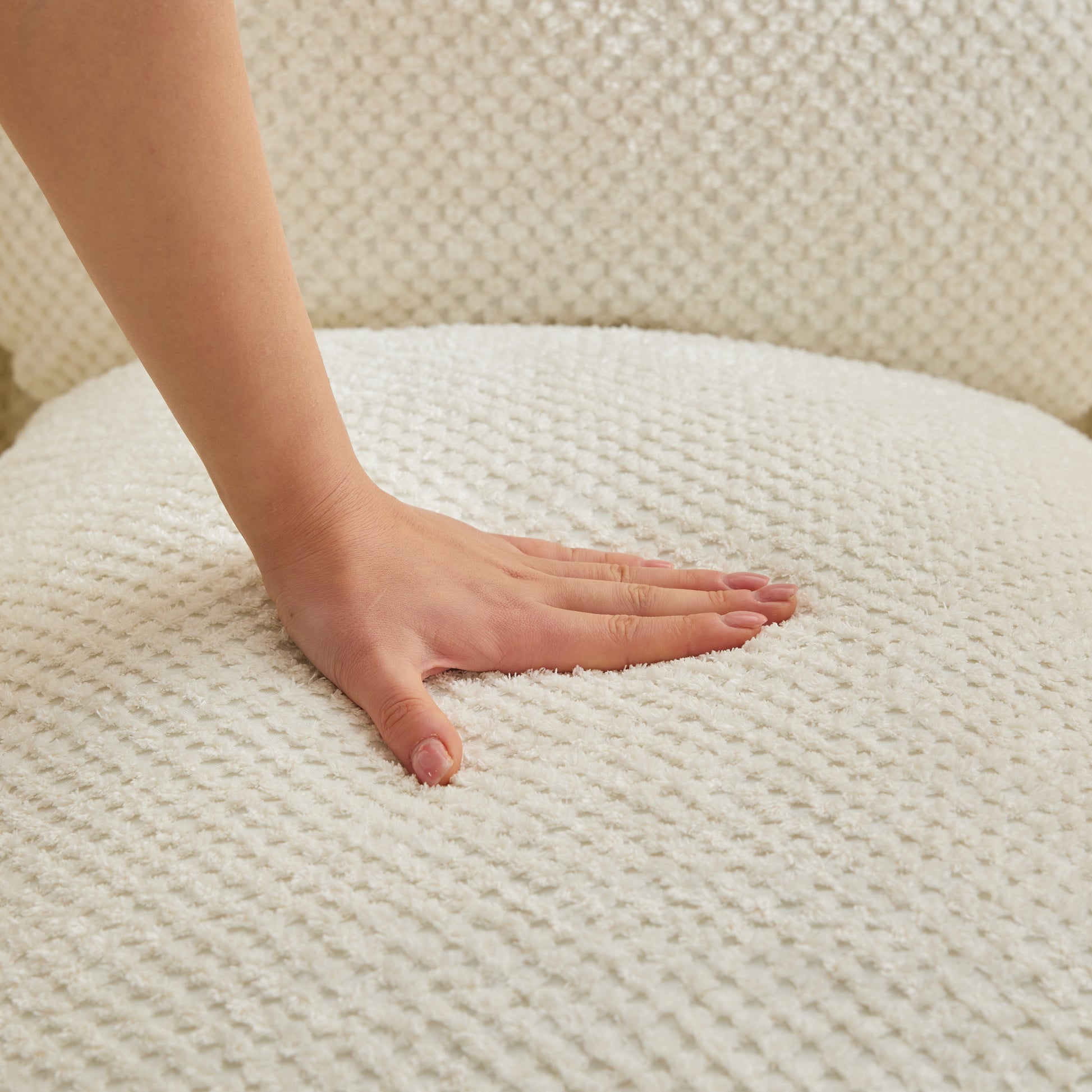 Hand touching plush cream boucle armchair fabric for comfort and texture