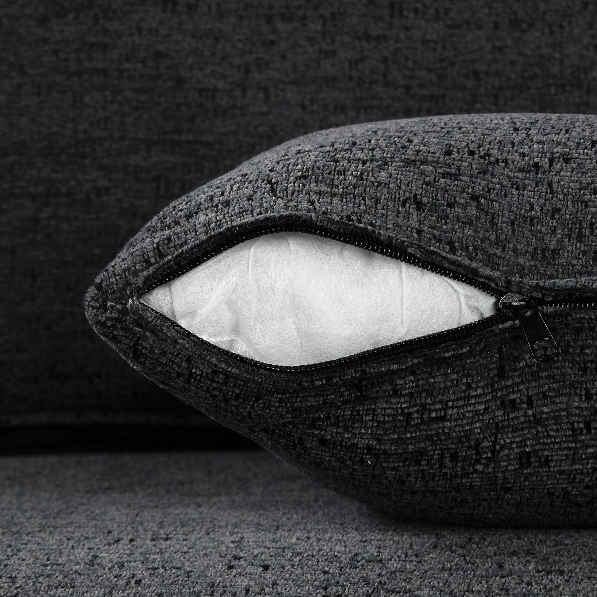 Dark gray textured throw pillow with visible white stuffing and black zipper detail