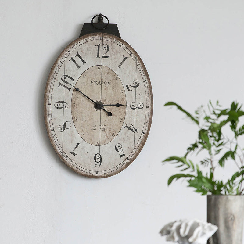 Oval distressed wall clock with French country design and black numerals