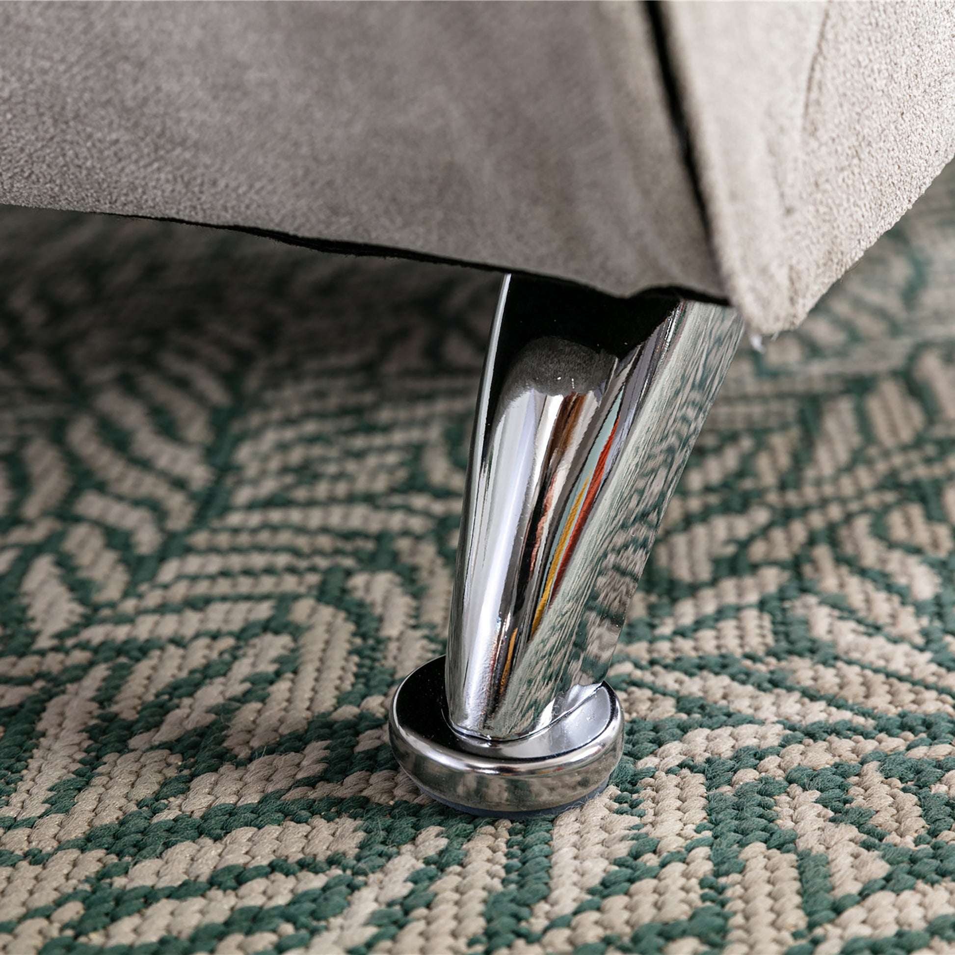 Chrome furniture leg with clear protector pad on patterned rug