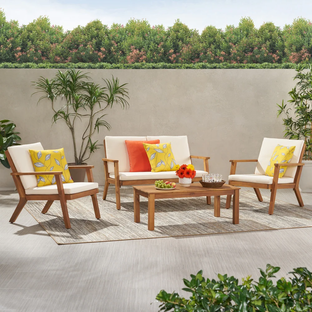 Wooden outdoor furniture set with cream cushions and decorative pillows on patio
