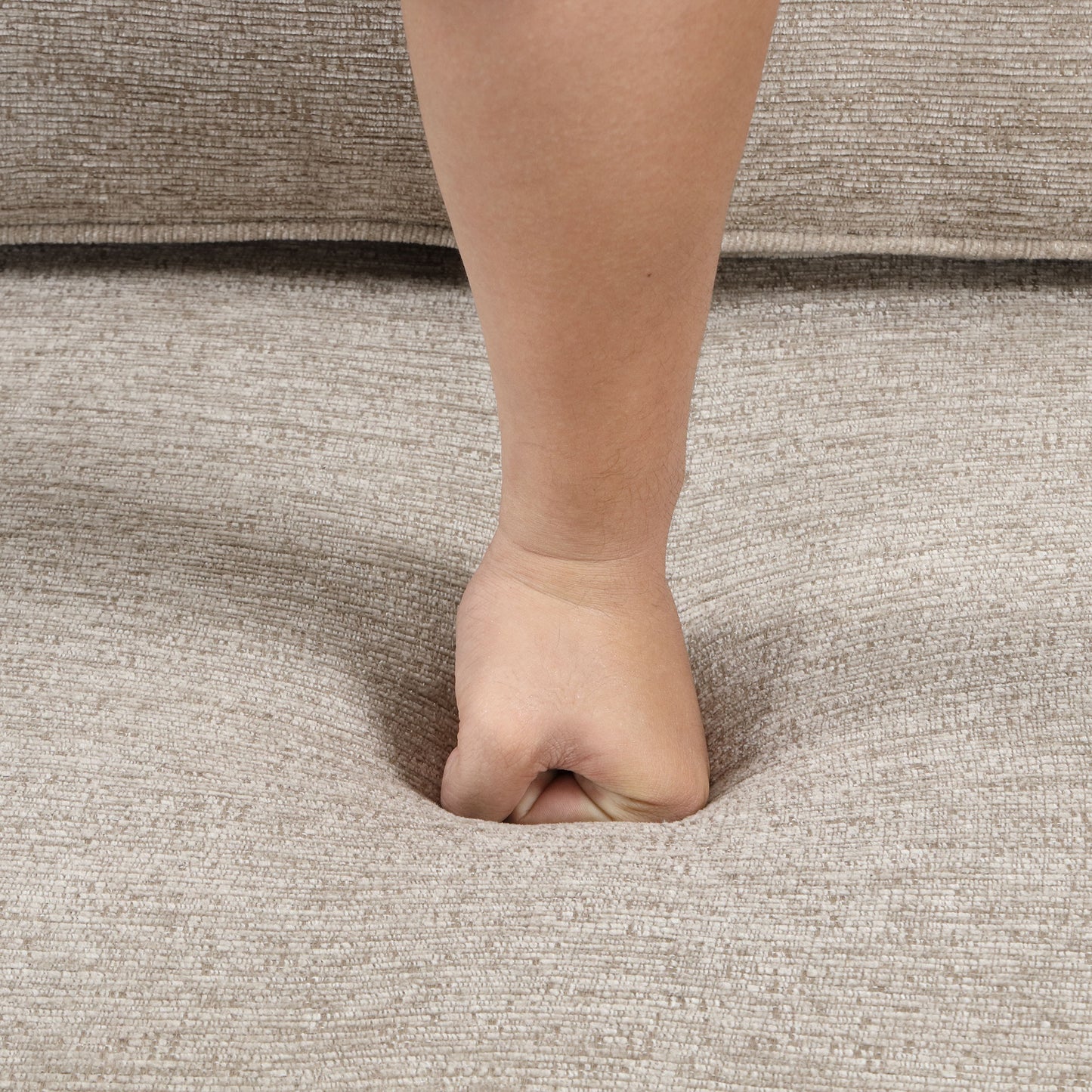 Fist indenting plush beige sofa cushion showcasing comfort and durability