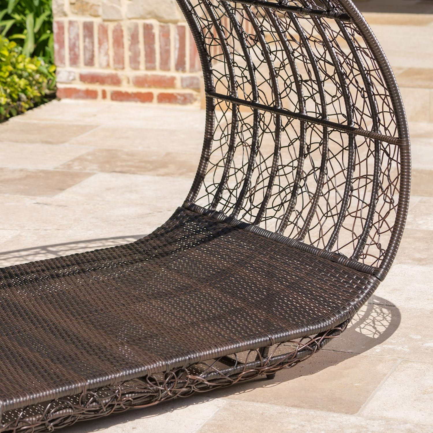 Dark brown rattan chaise lounge with woven texture and curved backrest
