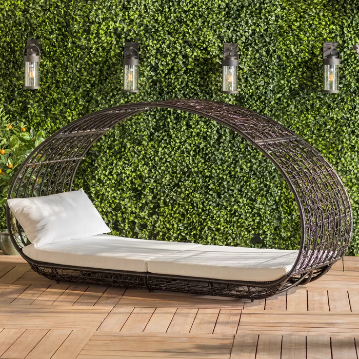 Oval wicker outdoor daybed with white cushions and a modern design