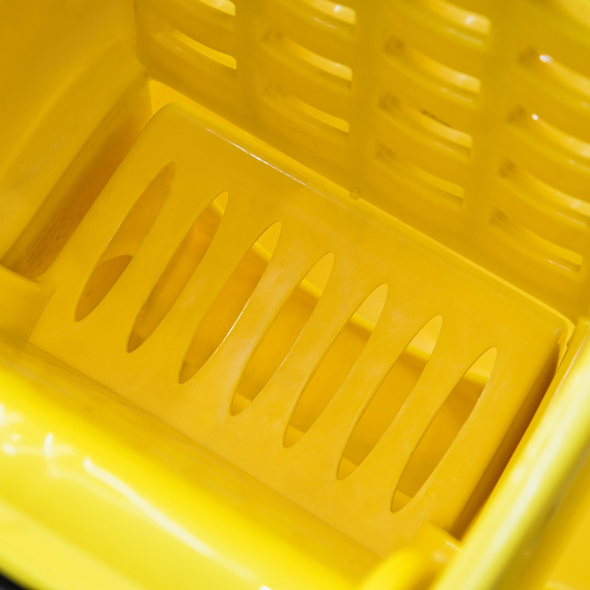Bright yellow plastic laundry basket with drainage holes