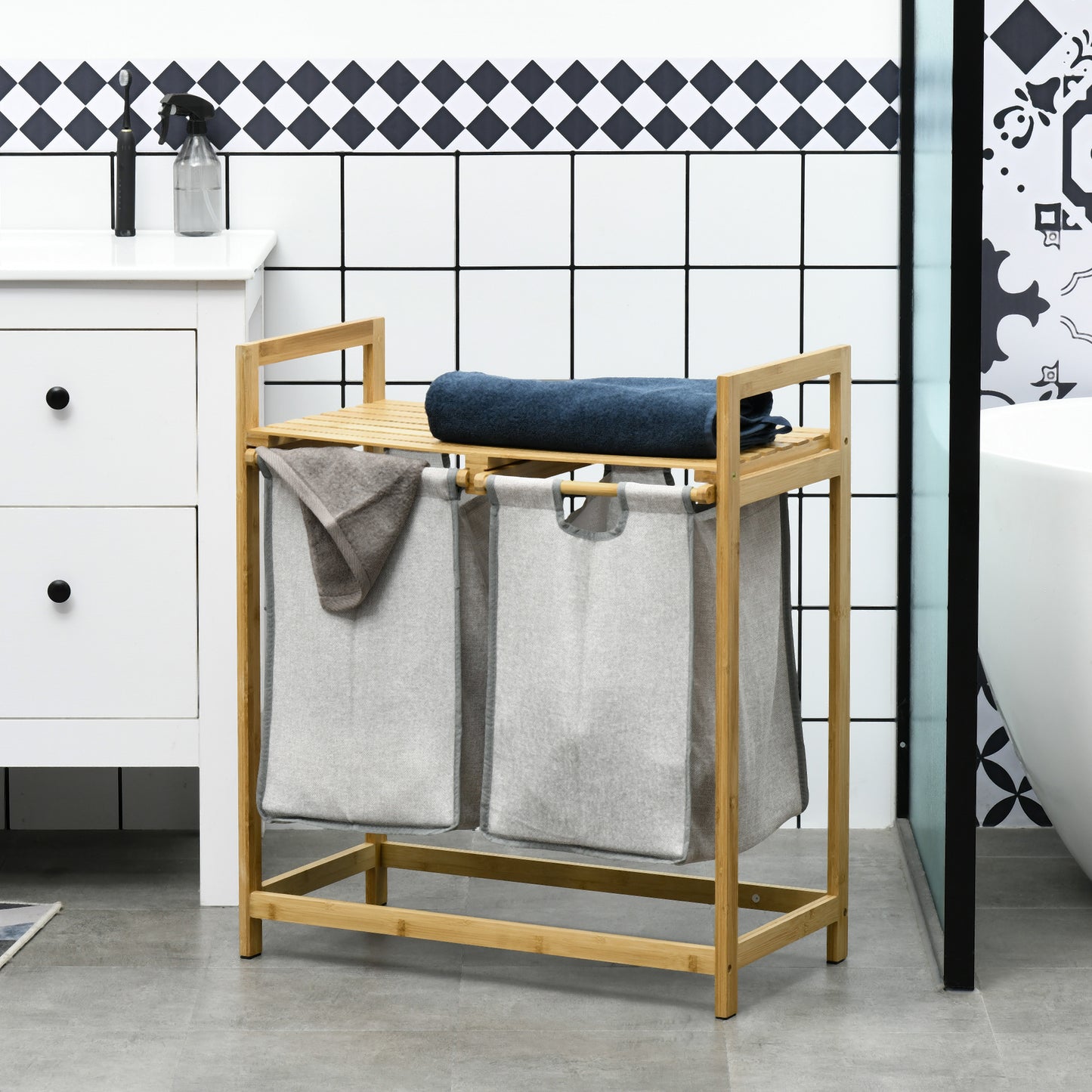 Natural bamboo laundry sorter with two gray fabric bins and top shelf for towels