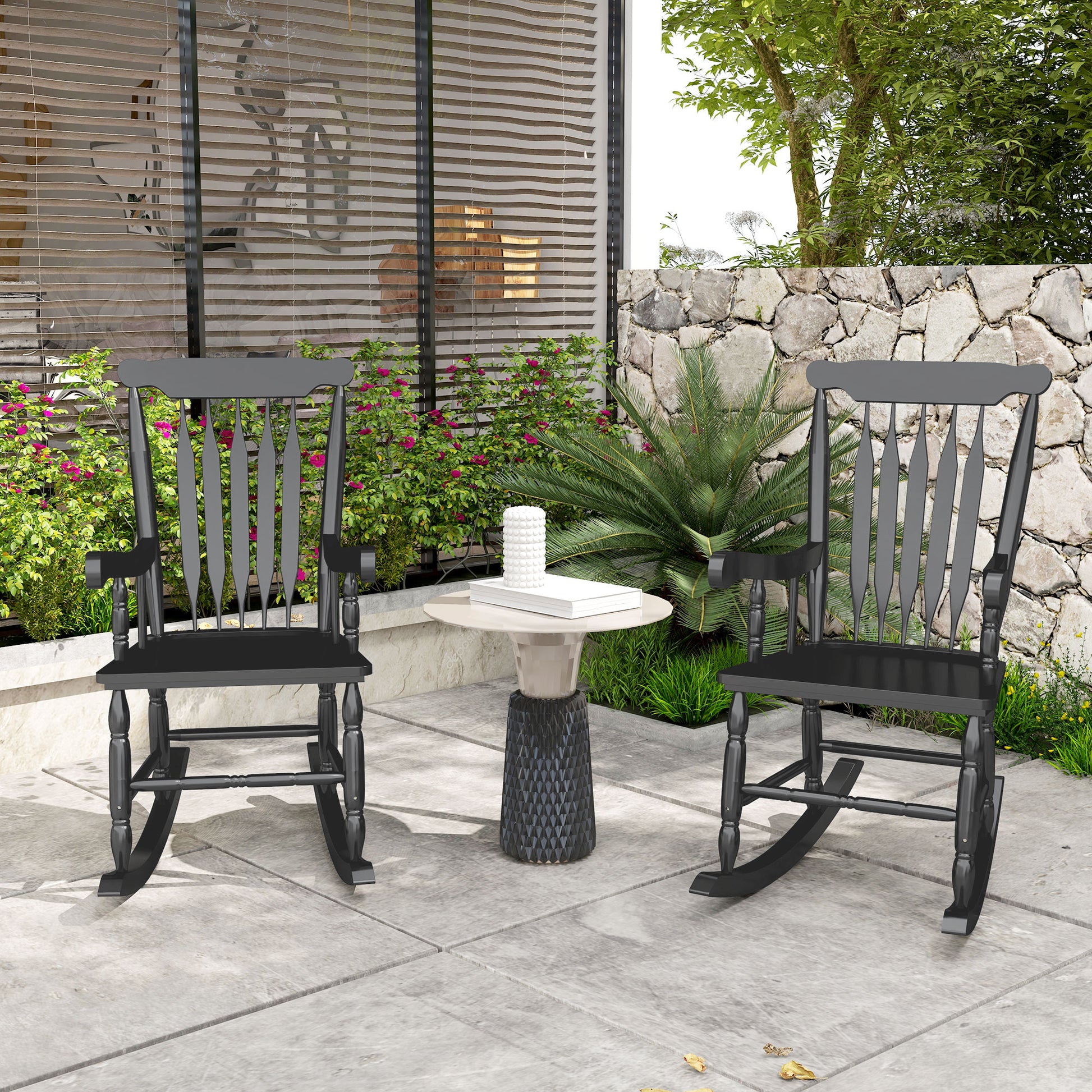 Two black wooden rocking chairs on a patio with a small side table