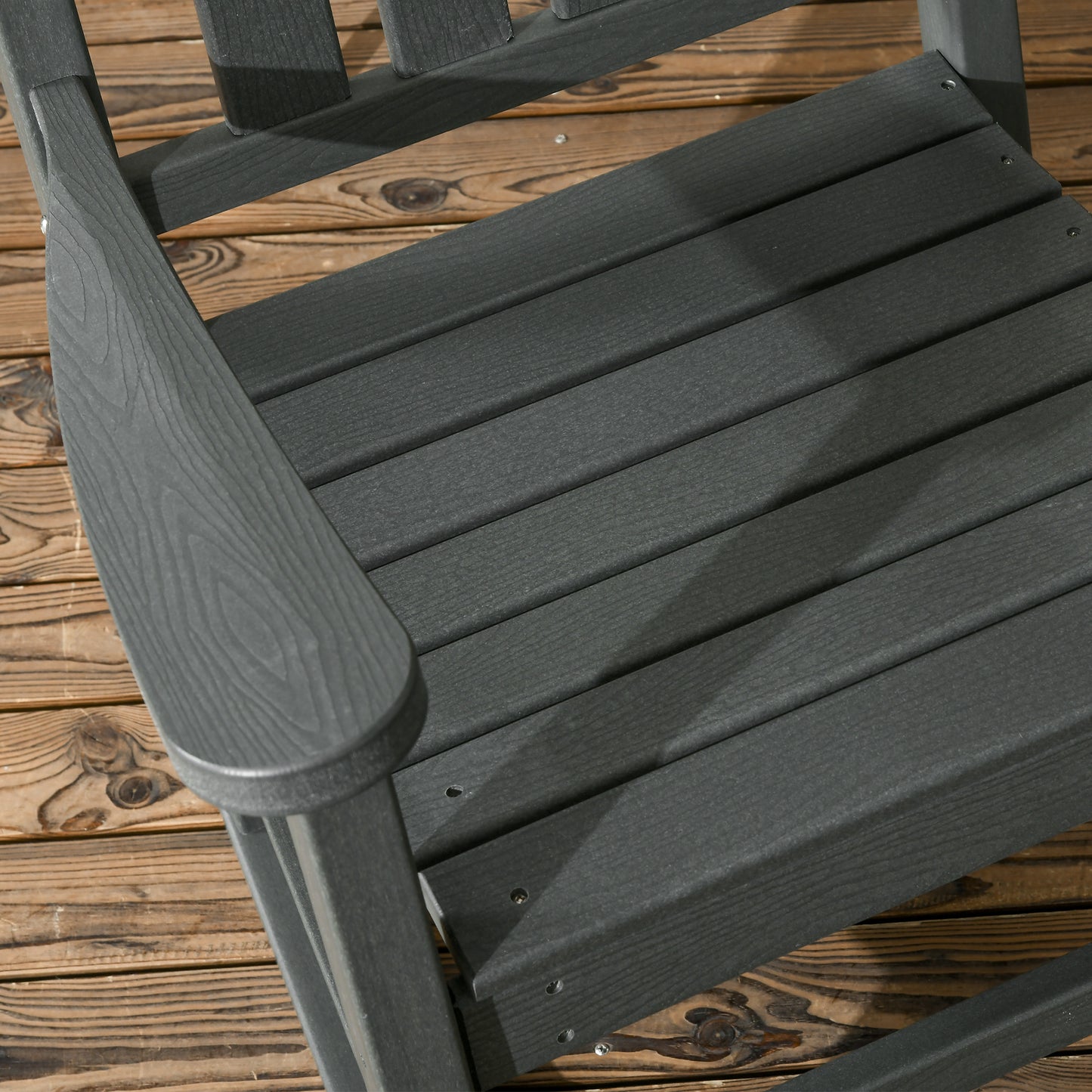 Closeup of dark gray Adirondack chair seat and armrest on wooden deck