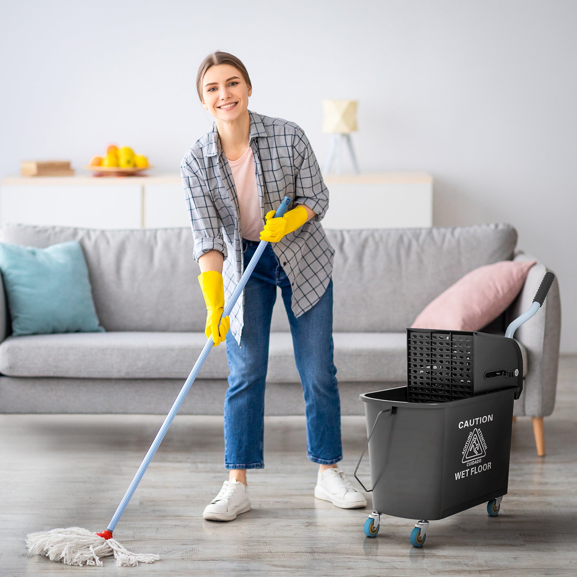 Woman mopping floor with a traditional string mop and a rolling mop bucket