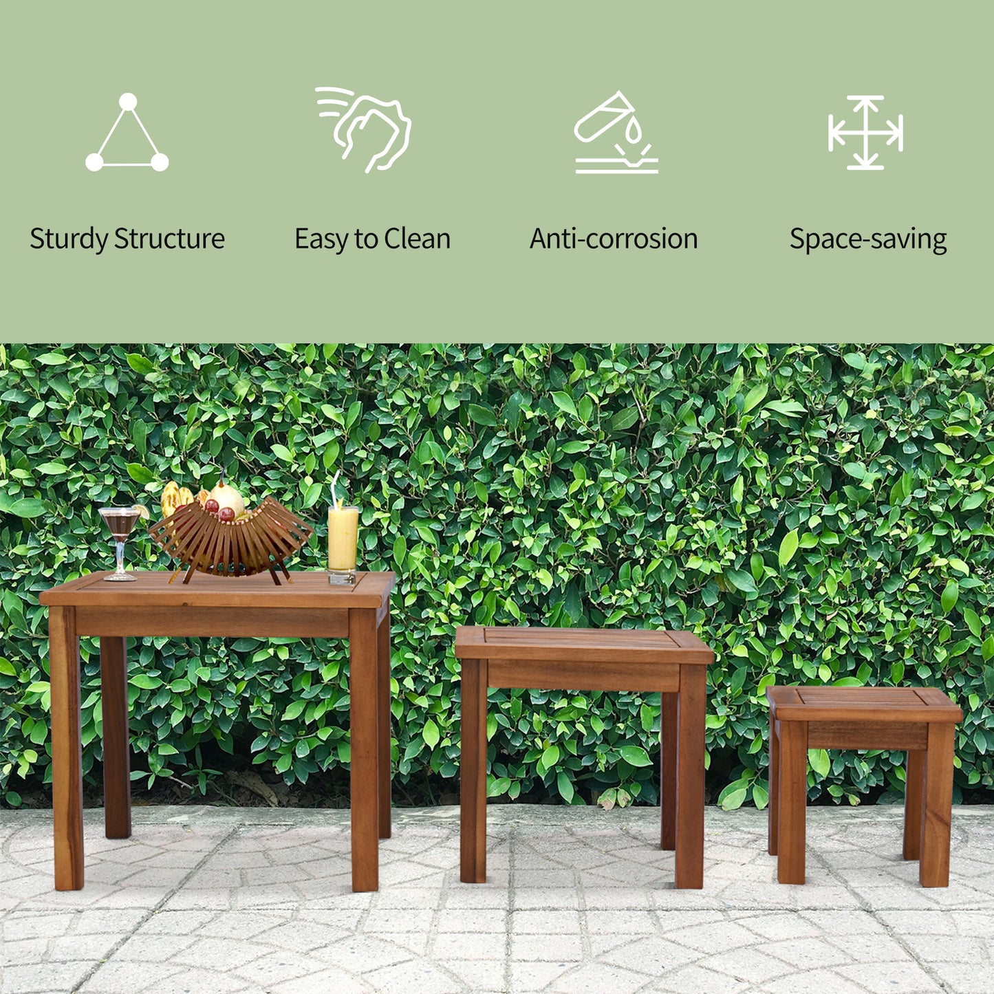 Three wooden outdoor tables one large and two small set against a green hedge