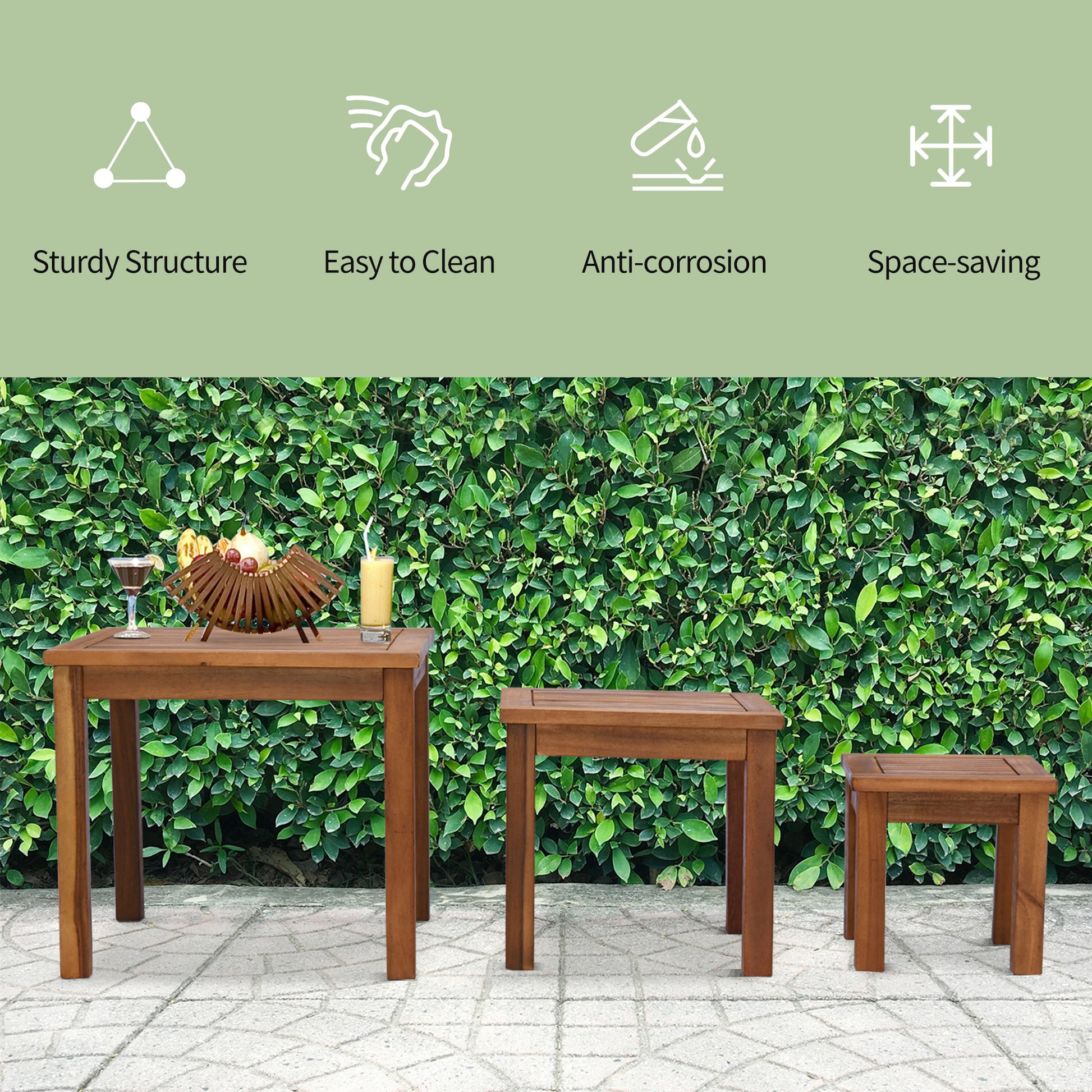 Three wooden outdoor tables one large and two small set against a green hedge