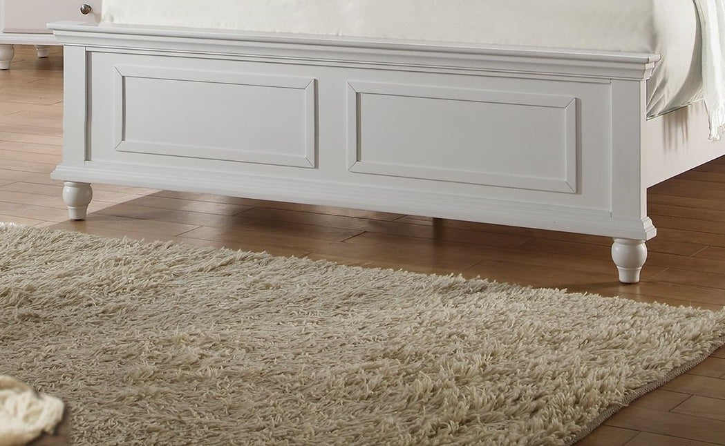 White wooden bed frame with paneled headboard and carved legs on a hardwood floor