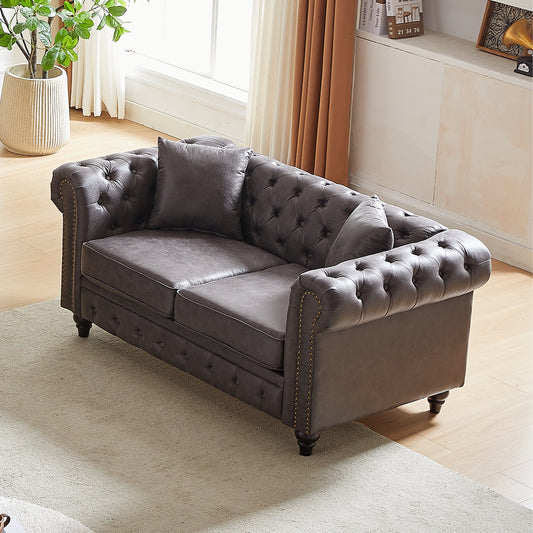 Dark gray tufted loveseat with rolled arms and bronze nailhead trim perfect for a living room