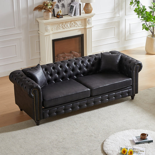 Black leather chesterfield sofa with tufted cushions and brass nailhead trim
