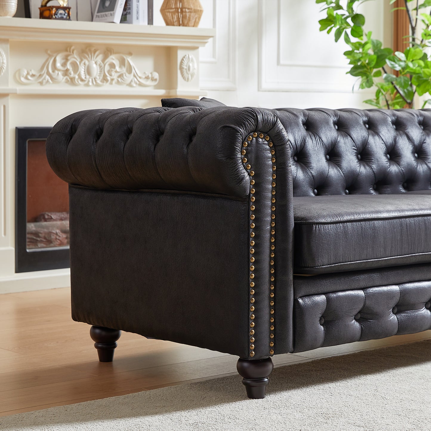Dark gray faux leather chesterfield sofa with button tufting and brass nailhead trim