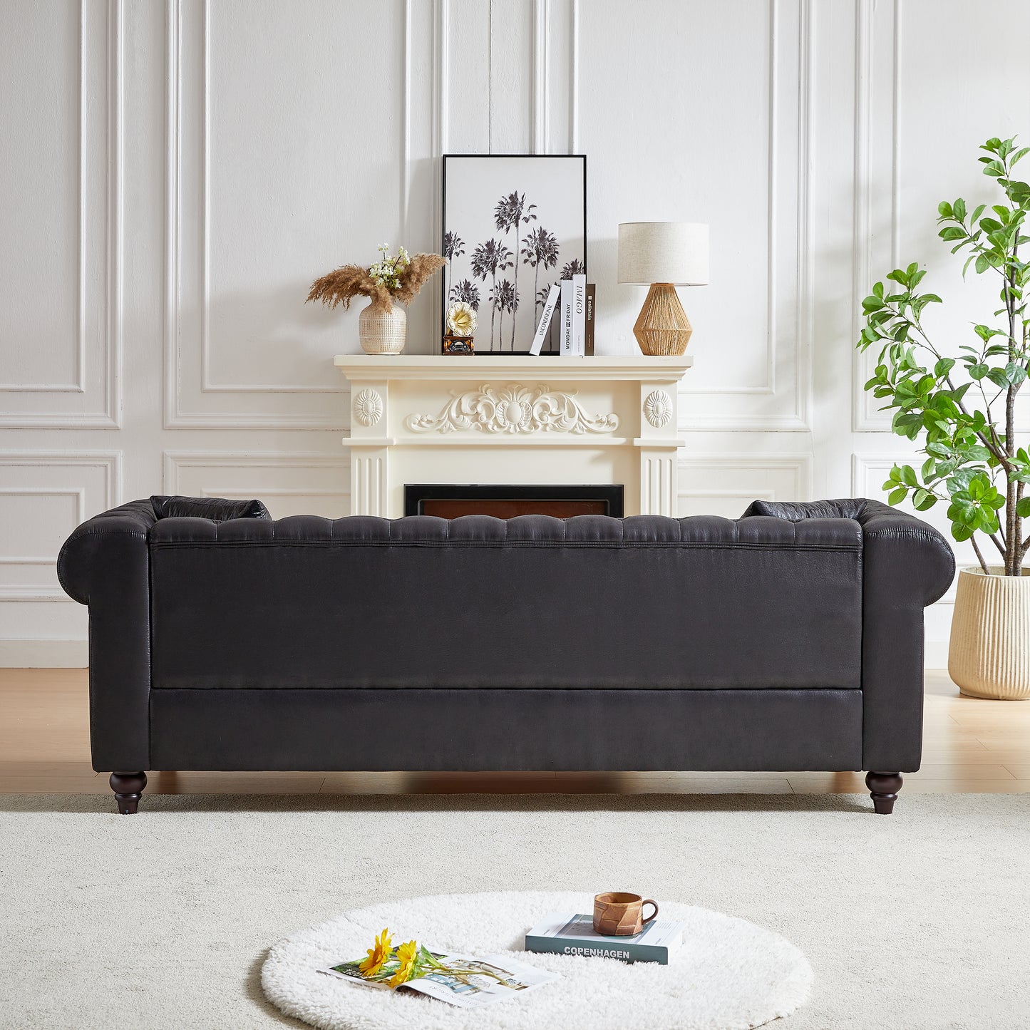 Dark gray tufted leather chesterfield sofa with rolled arms and dark wooden legs