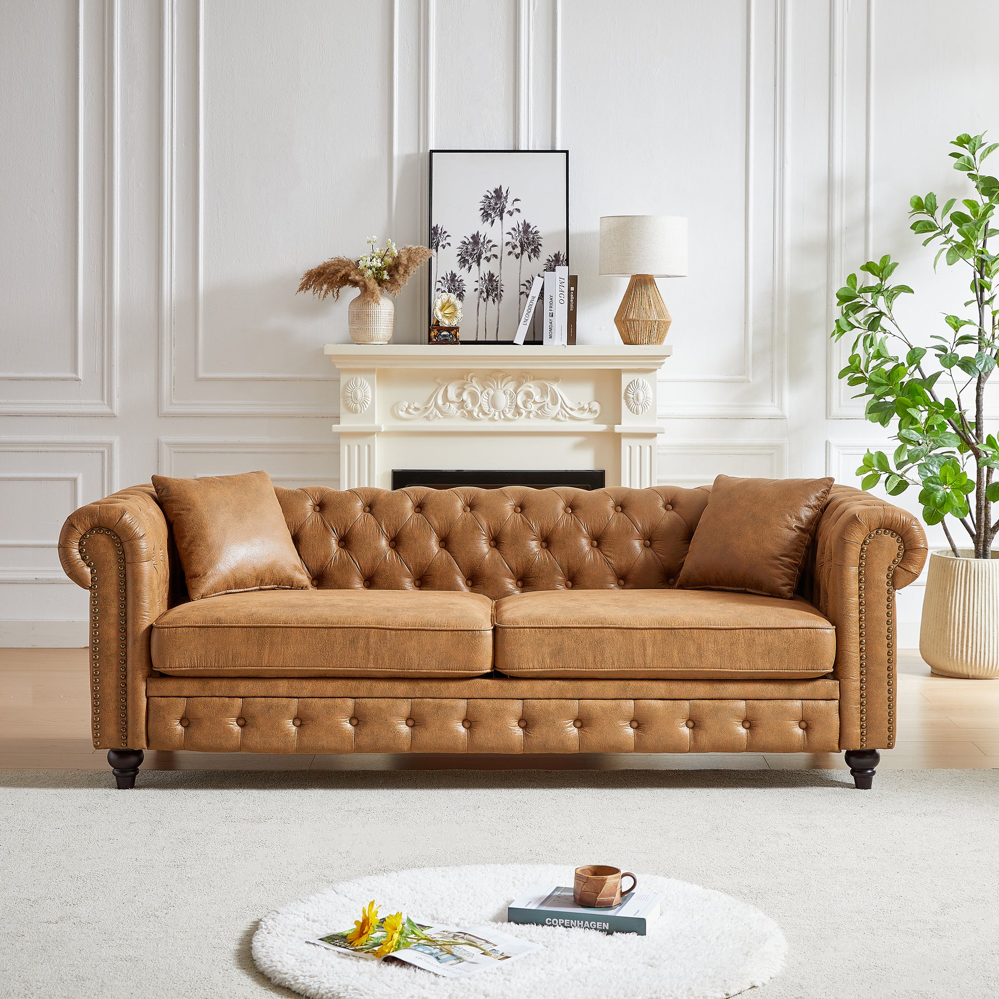 Tufted tan leather chesterfield sofa with silver nailhead trim and matching throw pillows