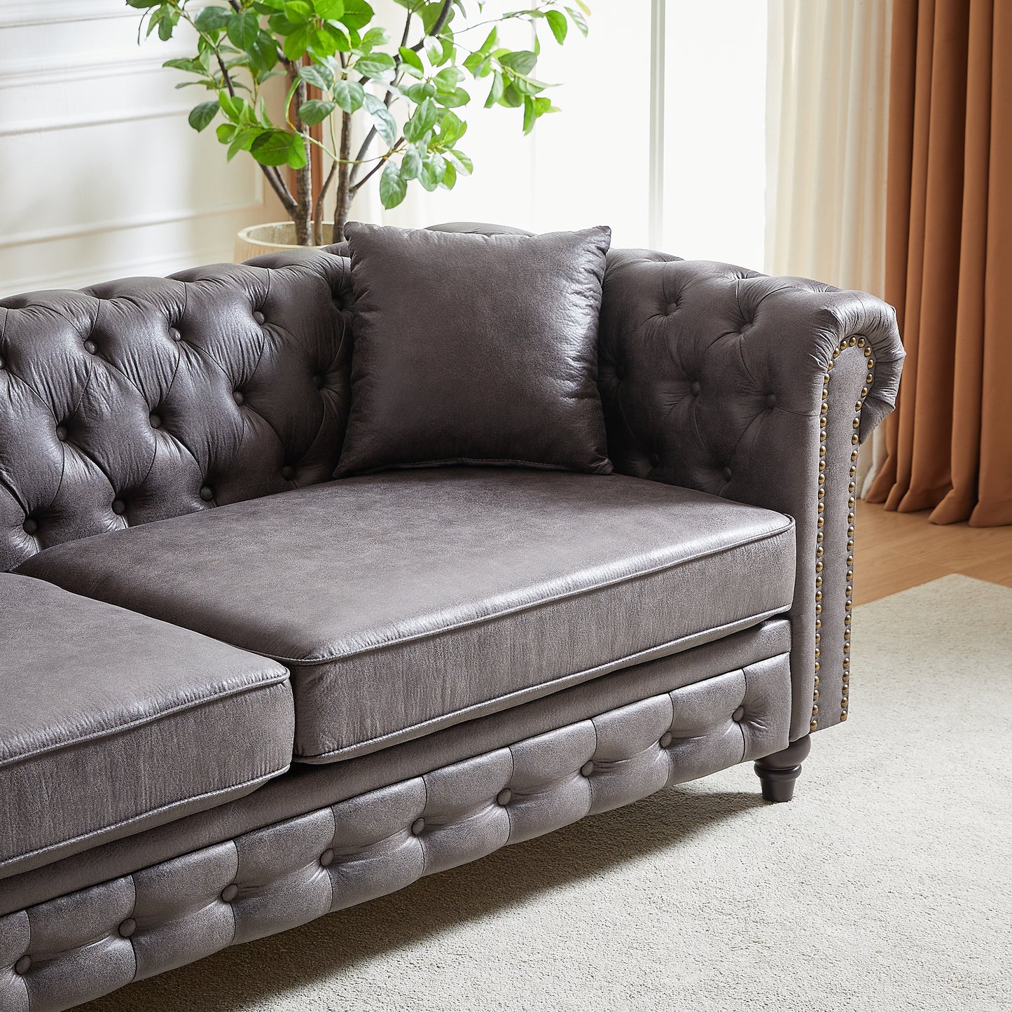 Gray leather chesterfield sofa with tufted details and brass nailhead trim