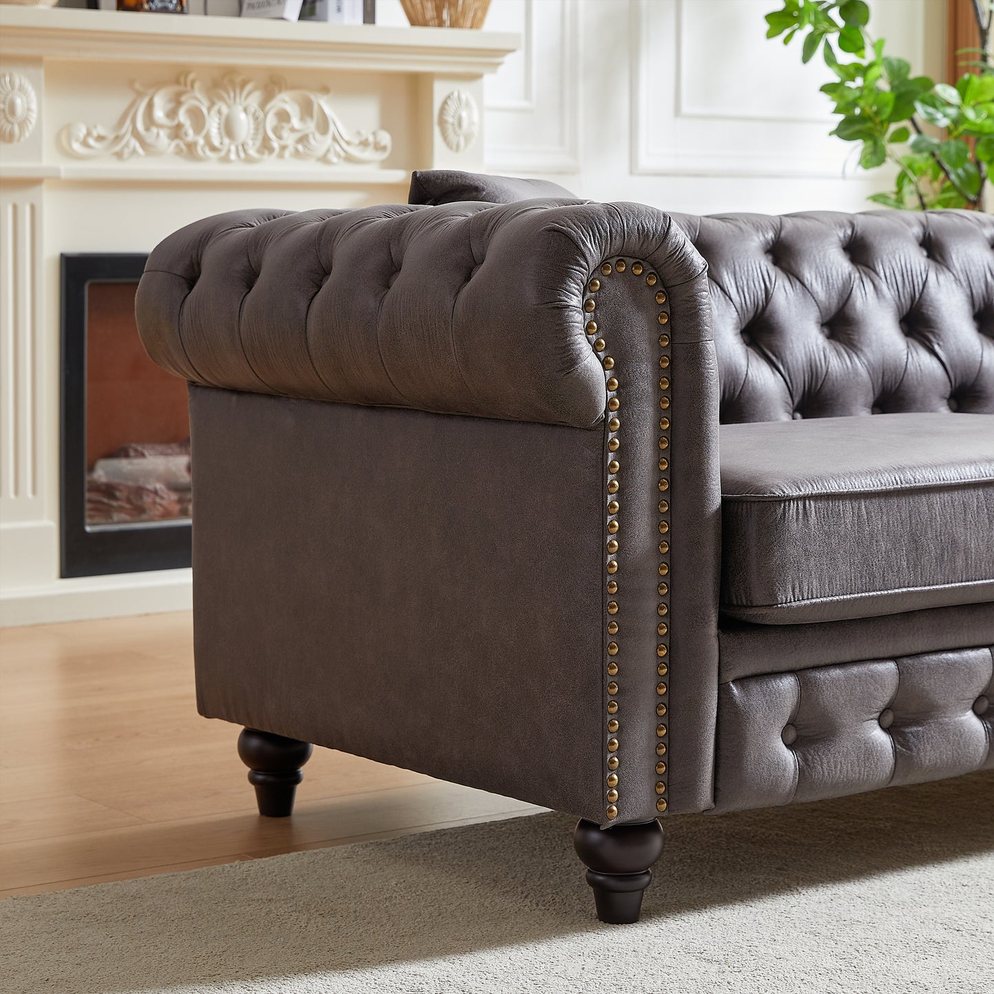 Dark grey tufted leather chesterfield sofa with brass nailhead trim