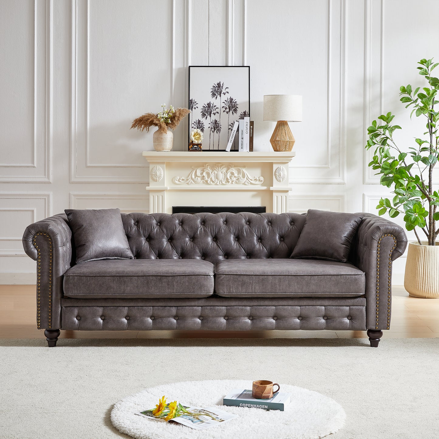 Gray faux leather chesterfield sofa with tufted back and antique brass nailhead trim