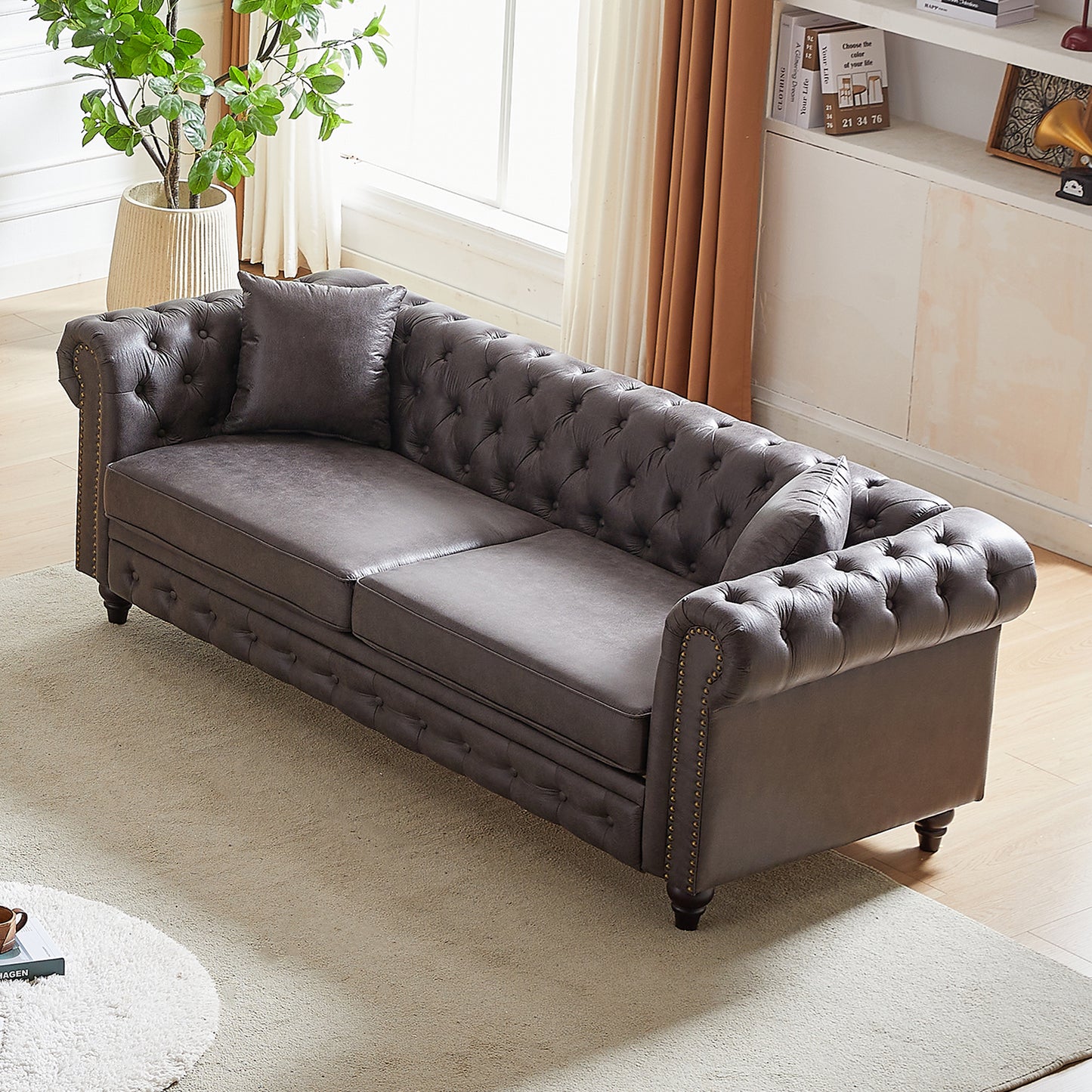 Dark brown tufted leather sofa with rolled arms and brass nailhead trim