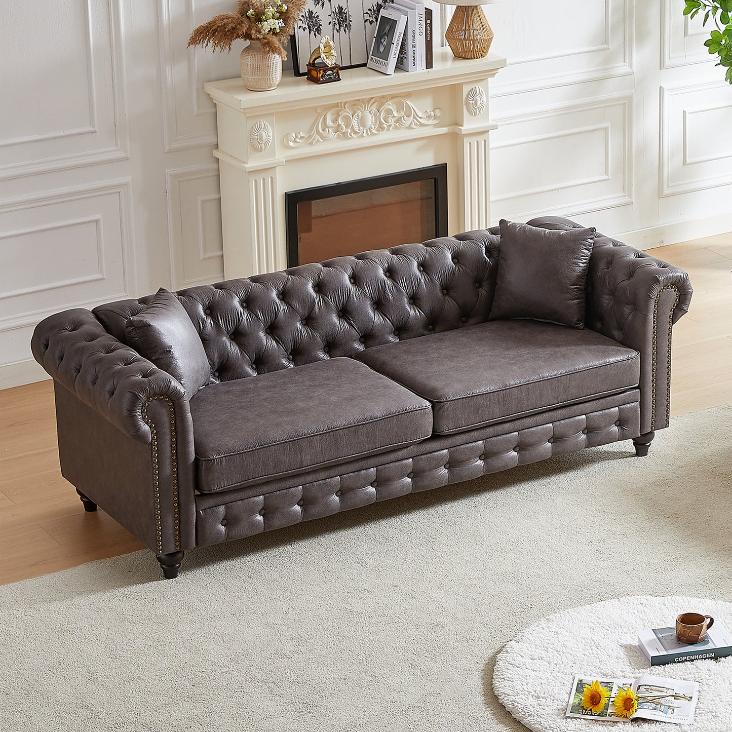 Tufted dark gray faux leather sofa with bronze nailhead trim and plush cushions a classic chesterfield style