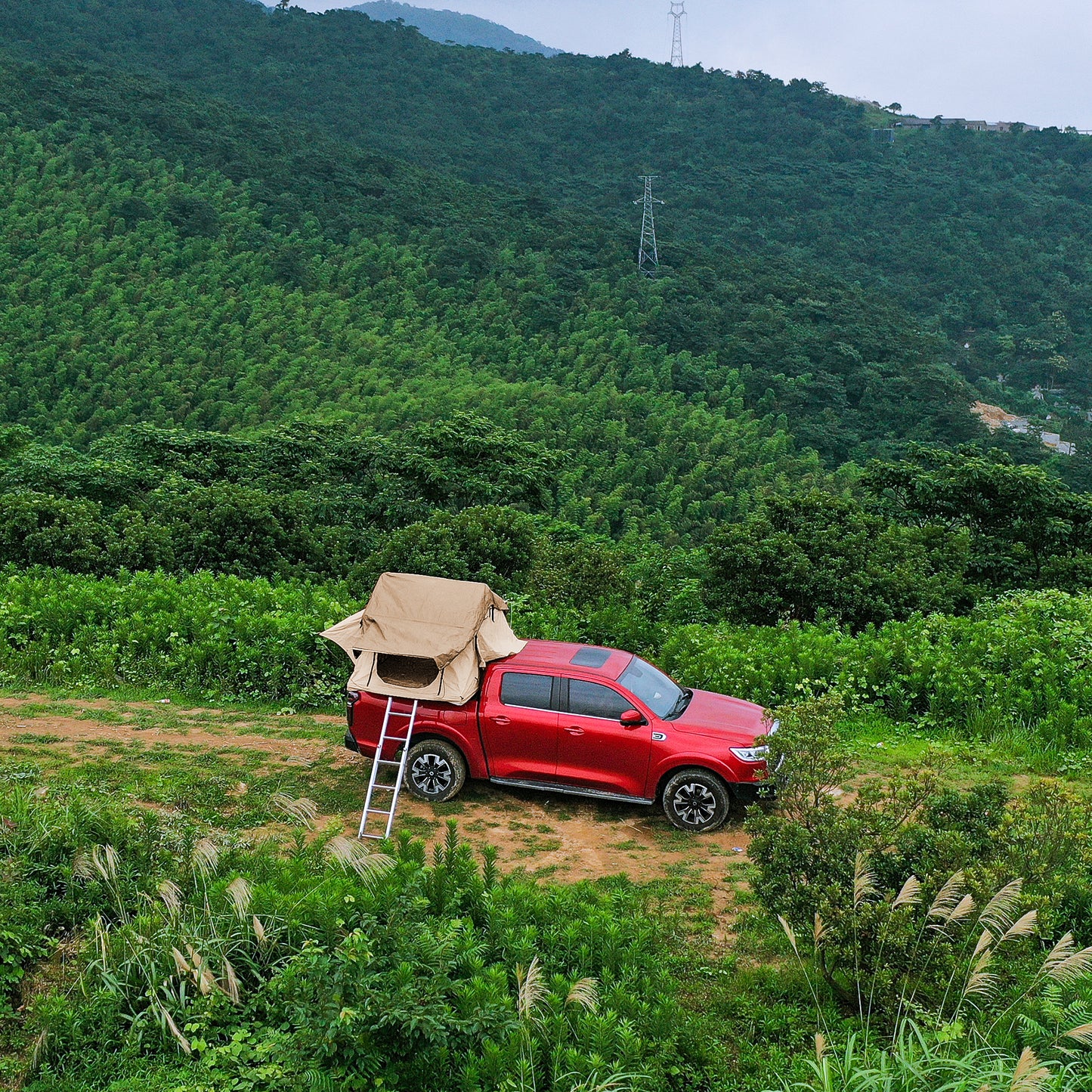 Red pickup truck with popup roof tent set up for camping outdoors