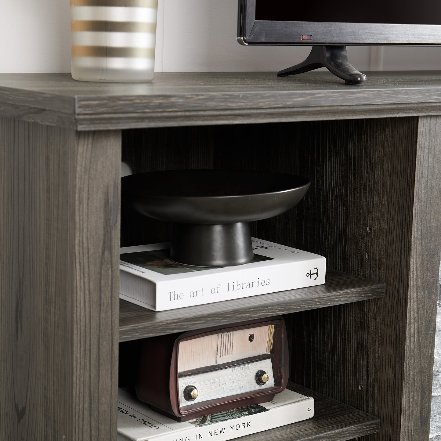 Dark grey wood media console with open shelves displaying decorative items