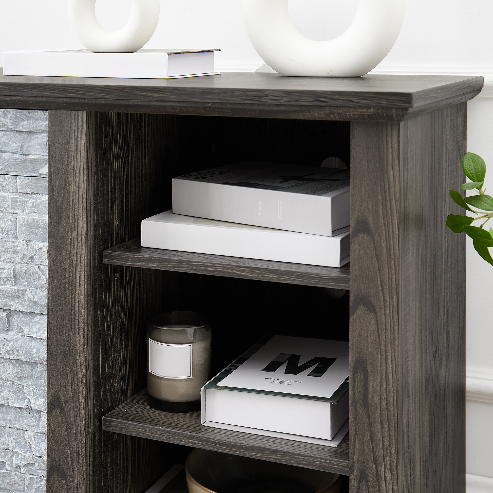 Dark gray wood media console with stone accent holding books and candle