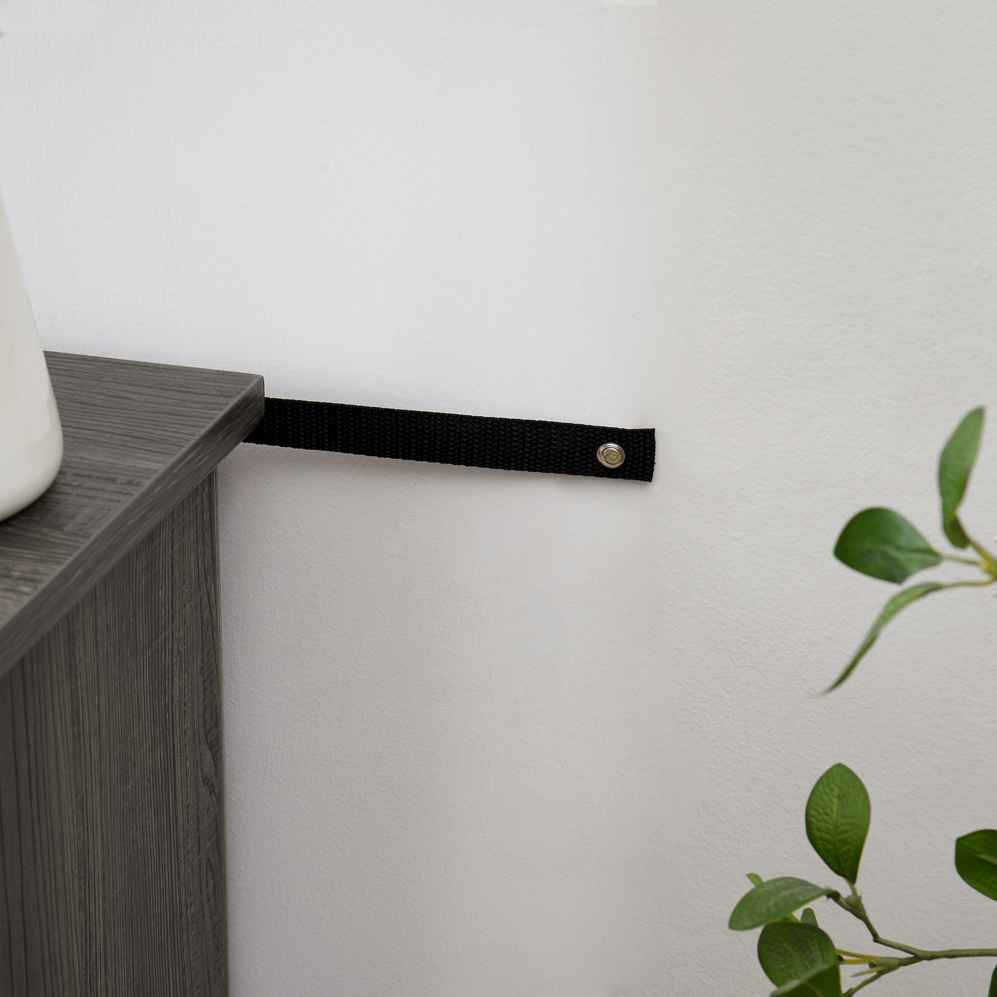 Black nylon furniture strap for antitip protection secures furniture to wall