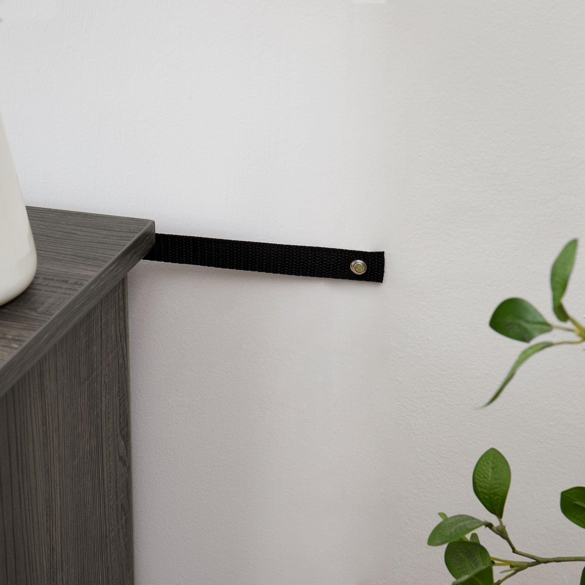 Black nylon furniture strap for antitip protection secures furniture to wall