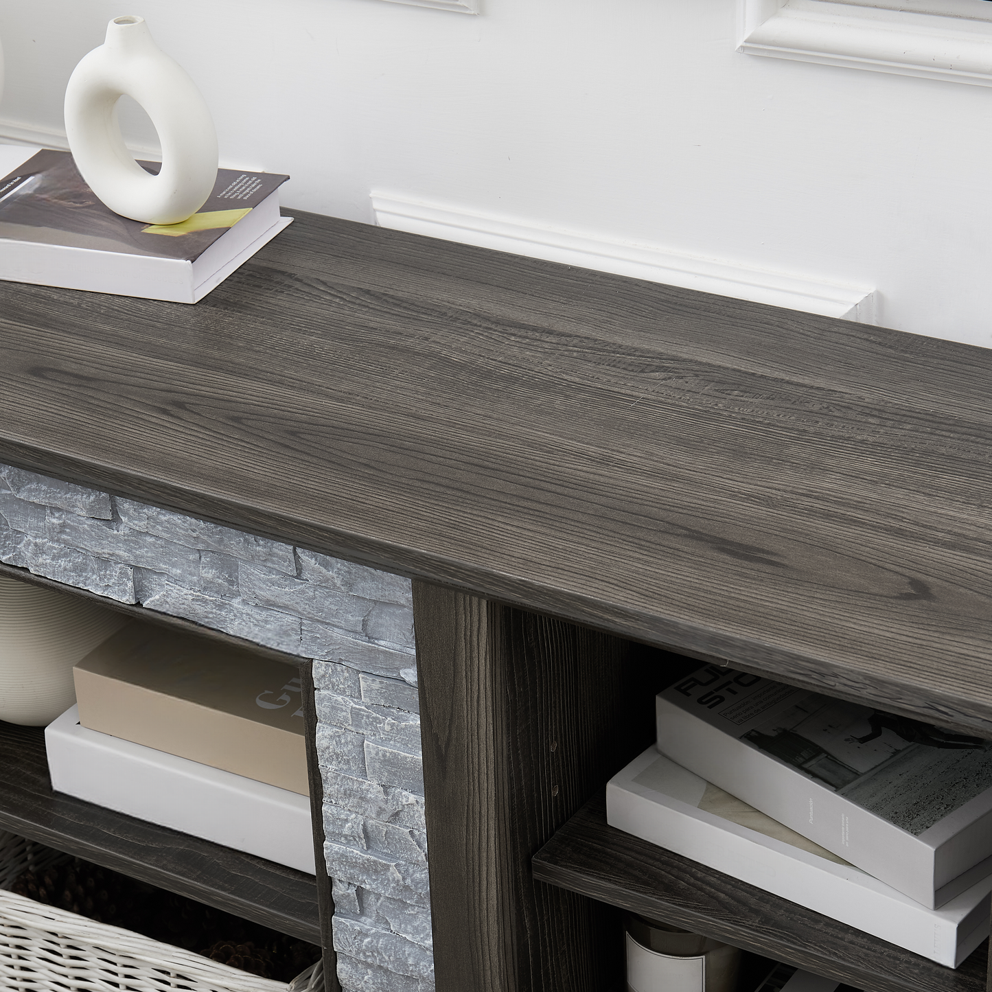 Dark wood media console with grey stone fireplace surround and decorative items