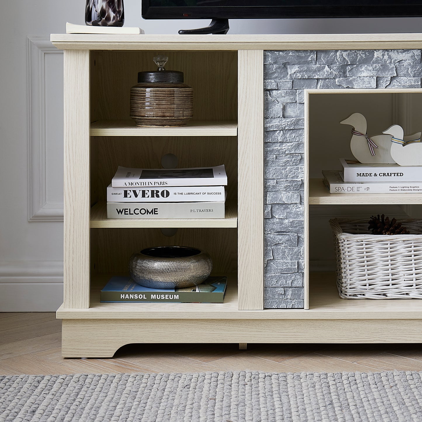 Light oak TV stand with grey stone accent displaying decorative items and books
